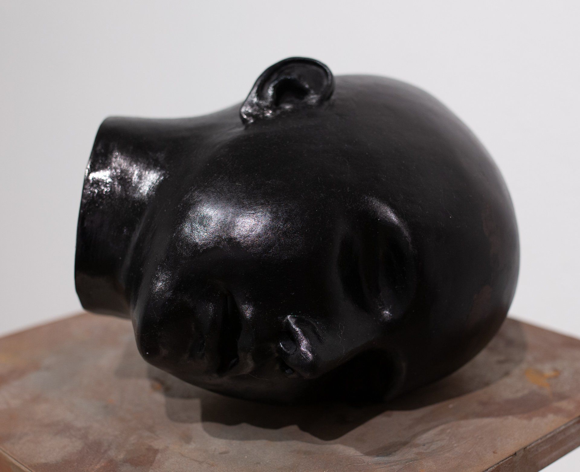 A black statue of a man 's head on a wooden block