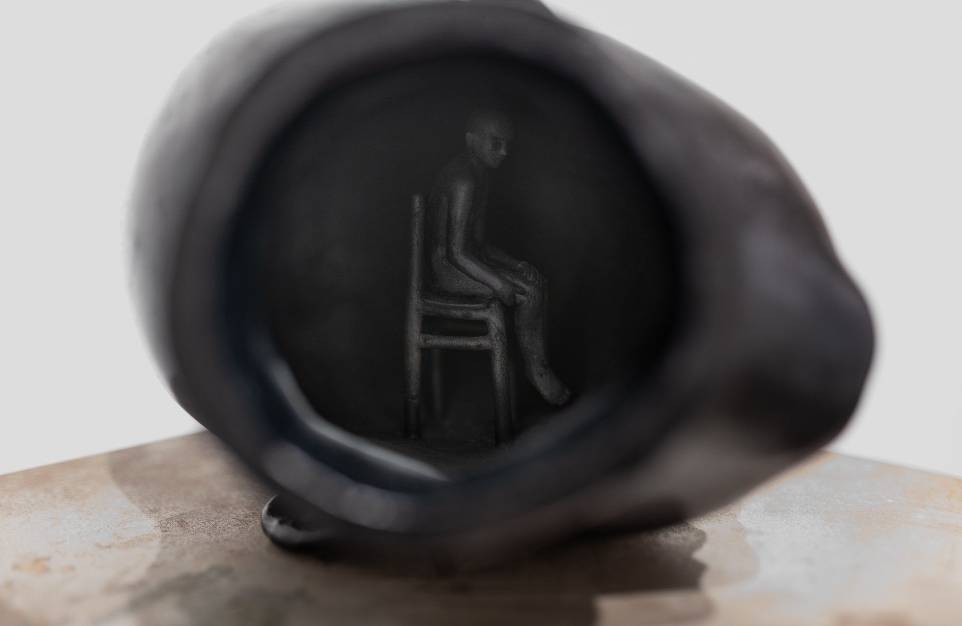 A black object with a drawing of a person sitting in a chair on it.