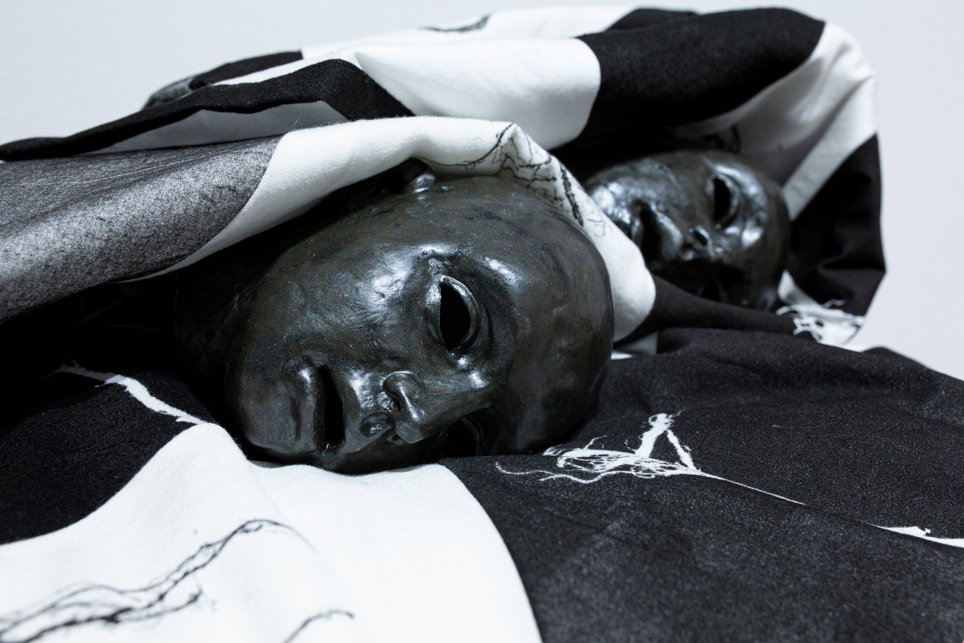 Two skulls are wrapped in a black and white blanket.