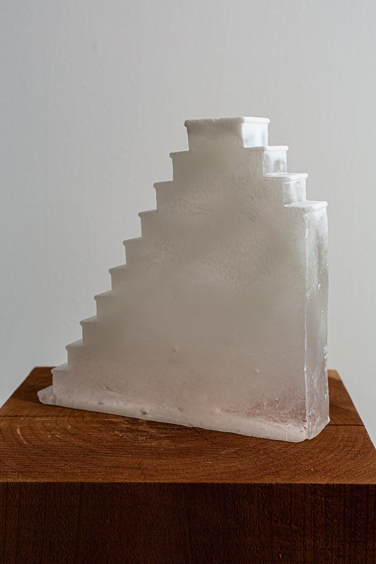 A sculpture of stairs made of ice is sitting on top of a wooden block.