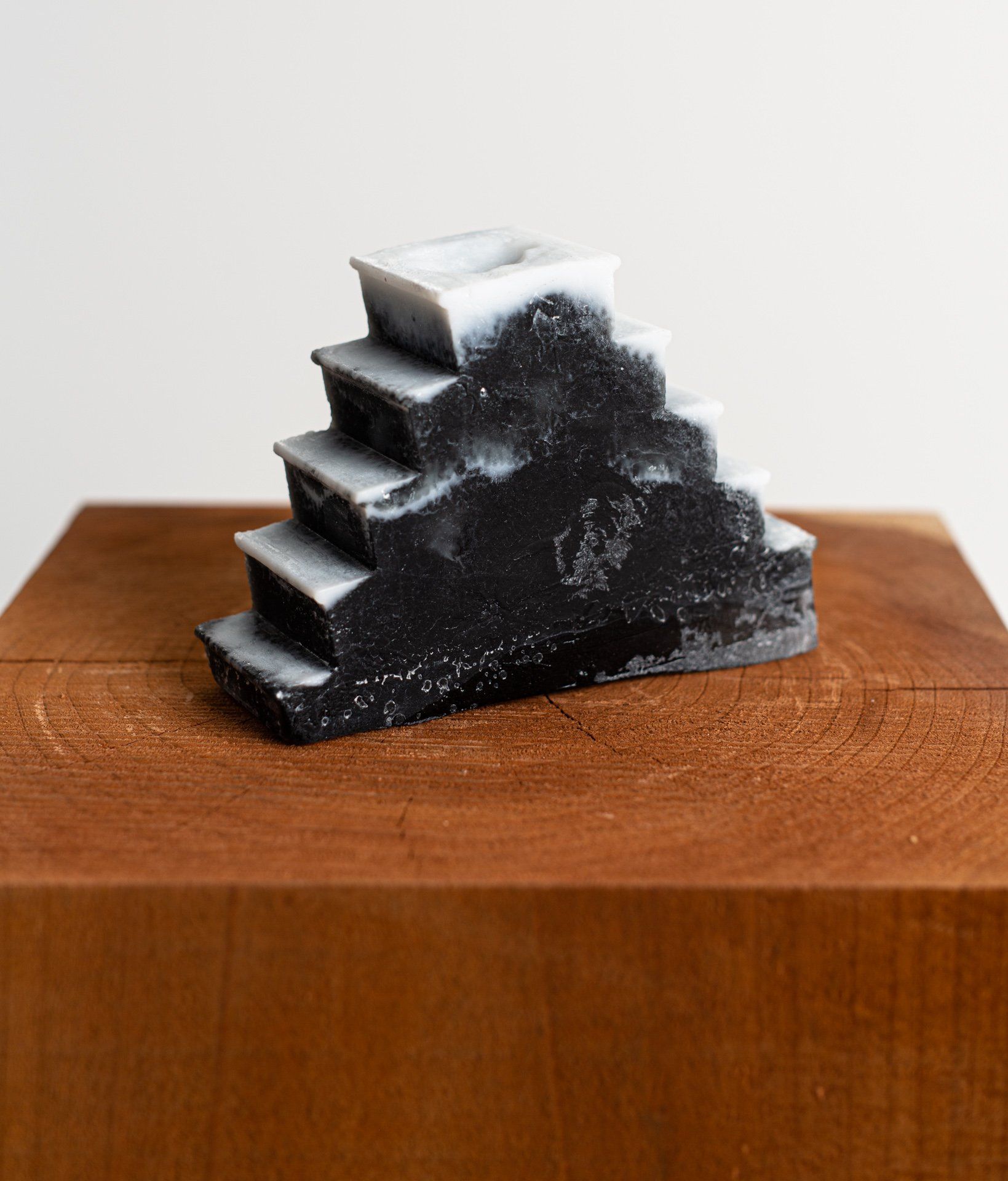 A black and white sculpture of stairs is sitting on top of a wooden block.