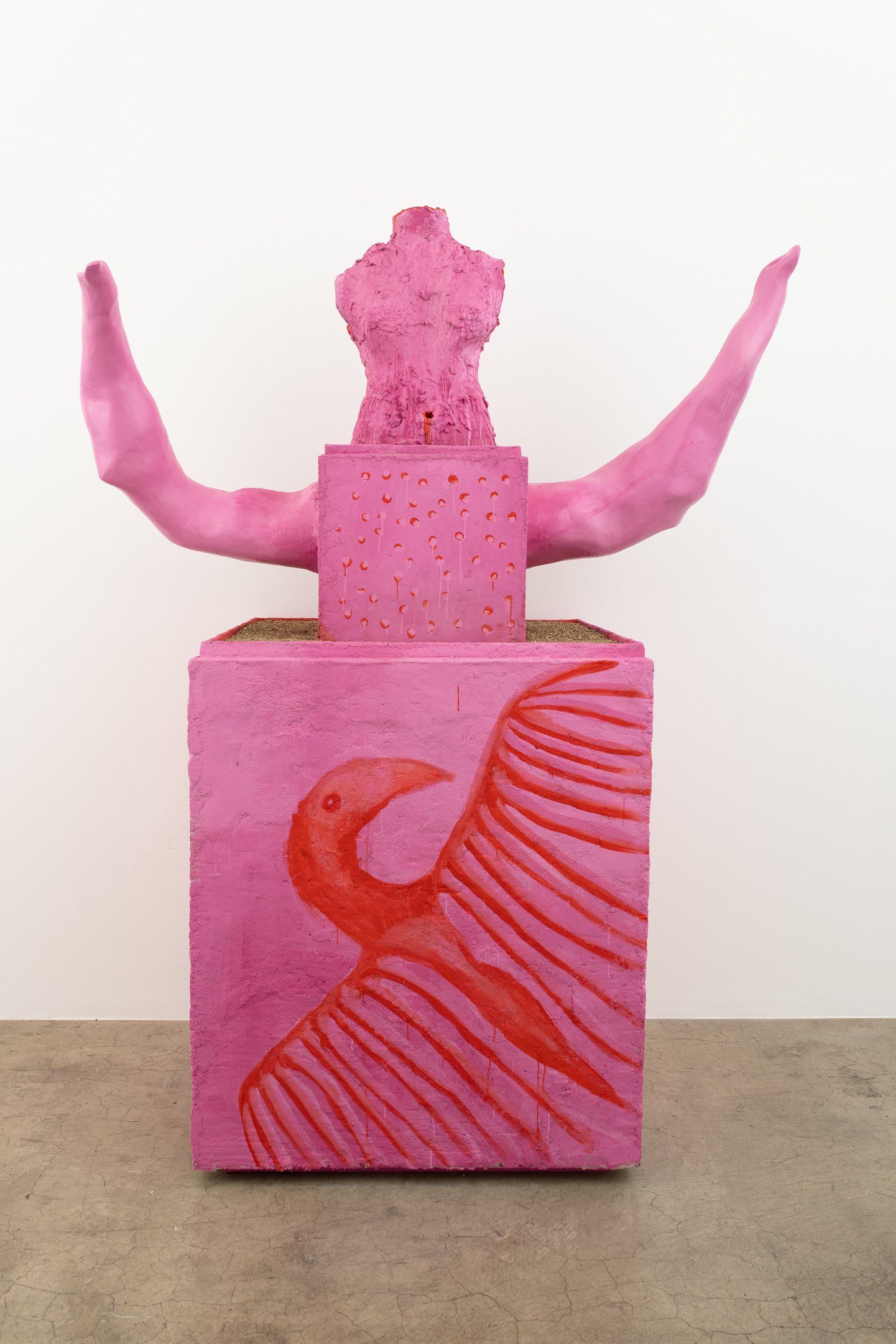 A pink sculpture with horns and wings is sitting on top of a pink box.