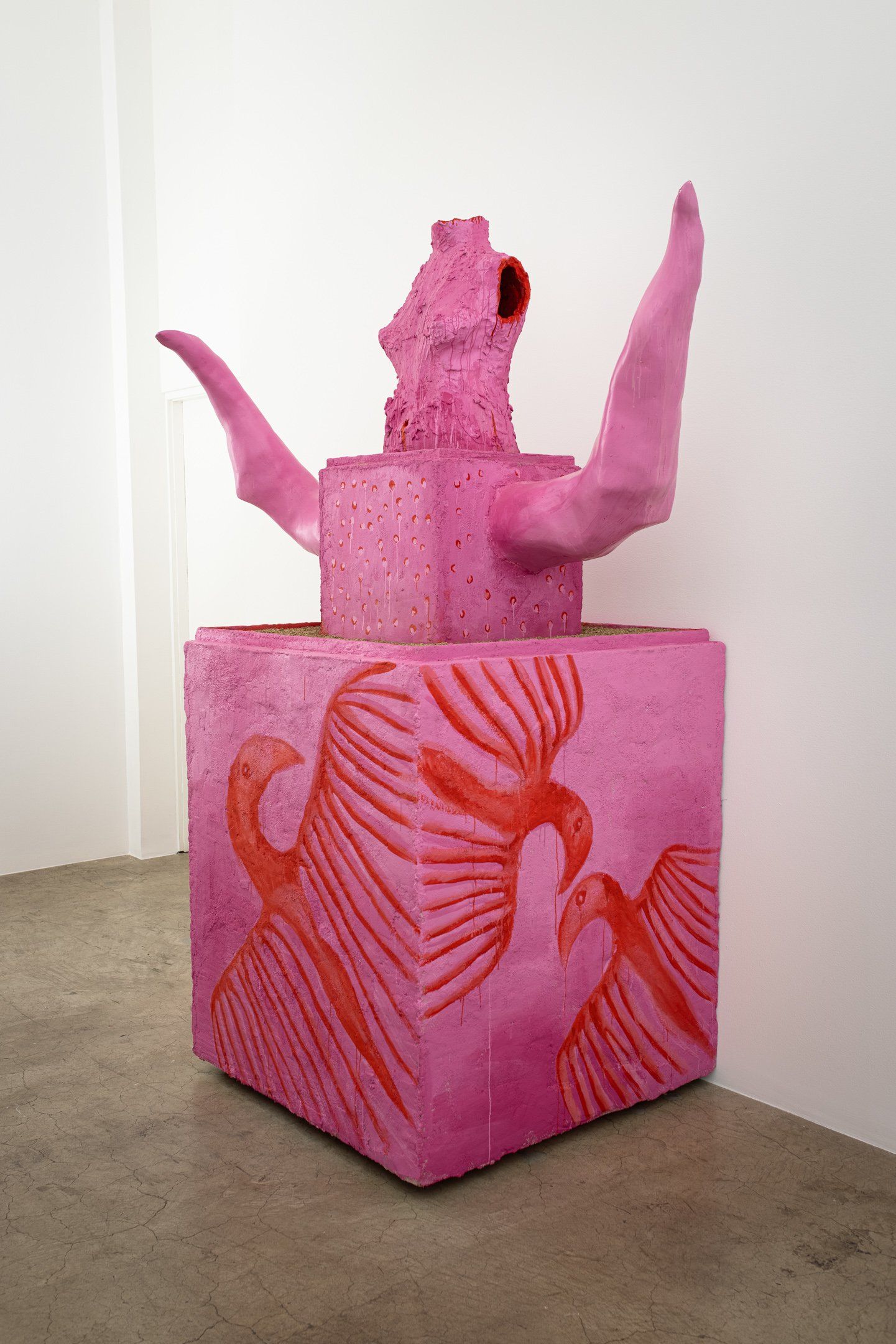 A pink sculpture with a bird on it is sitting on top of a pink box.