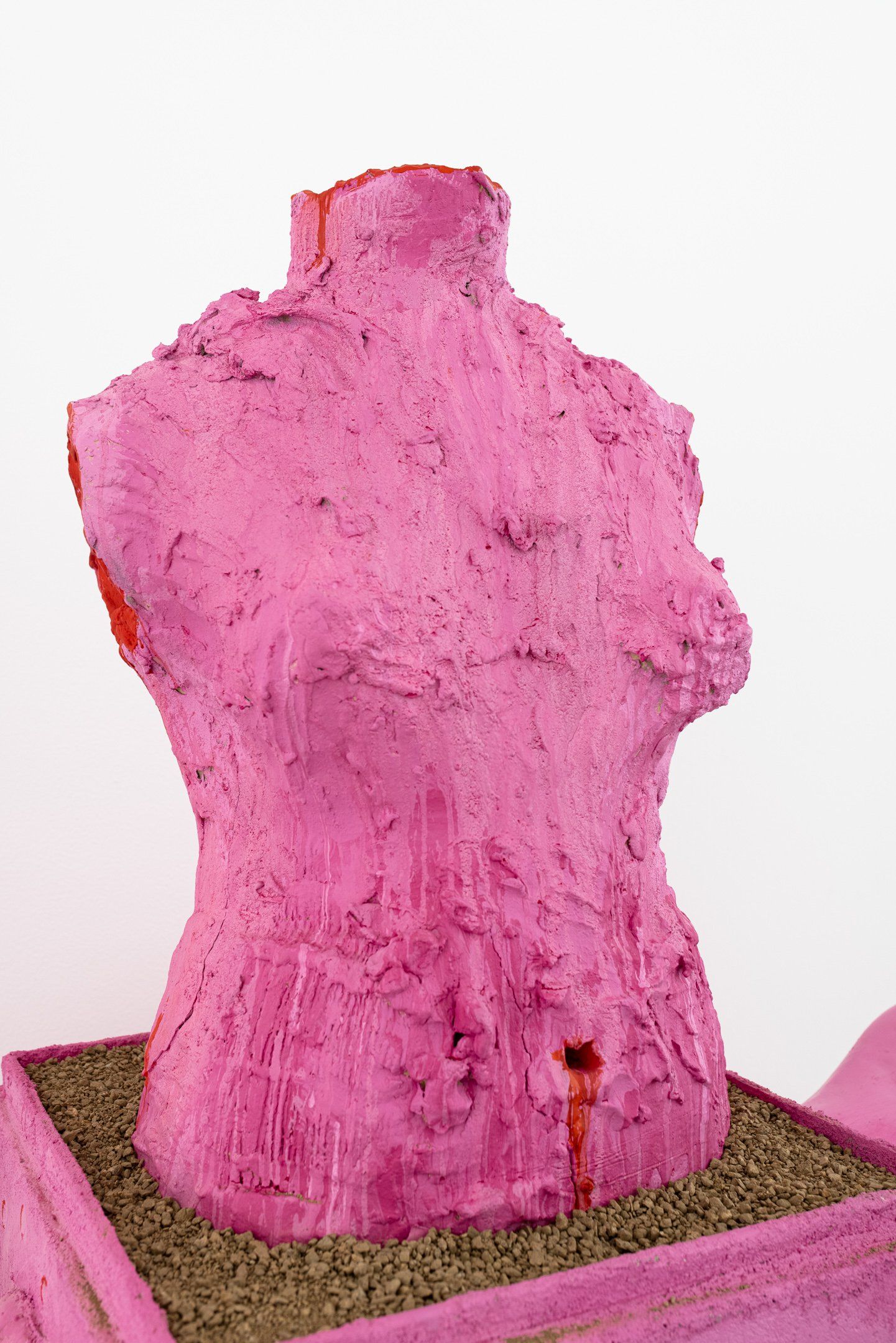 A pink statue of a woman 's torso is sitting on top of a pink box.