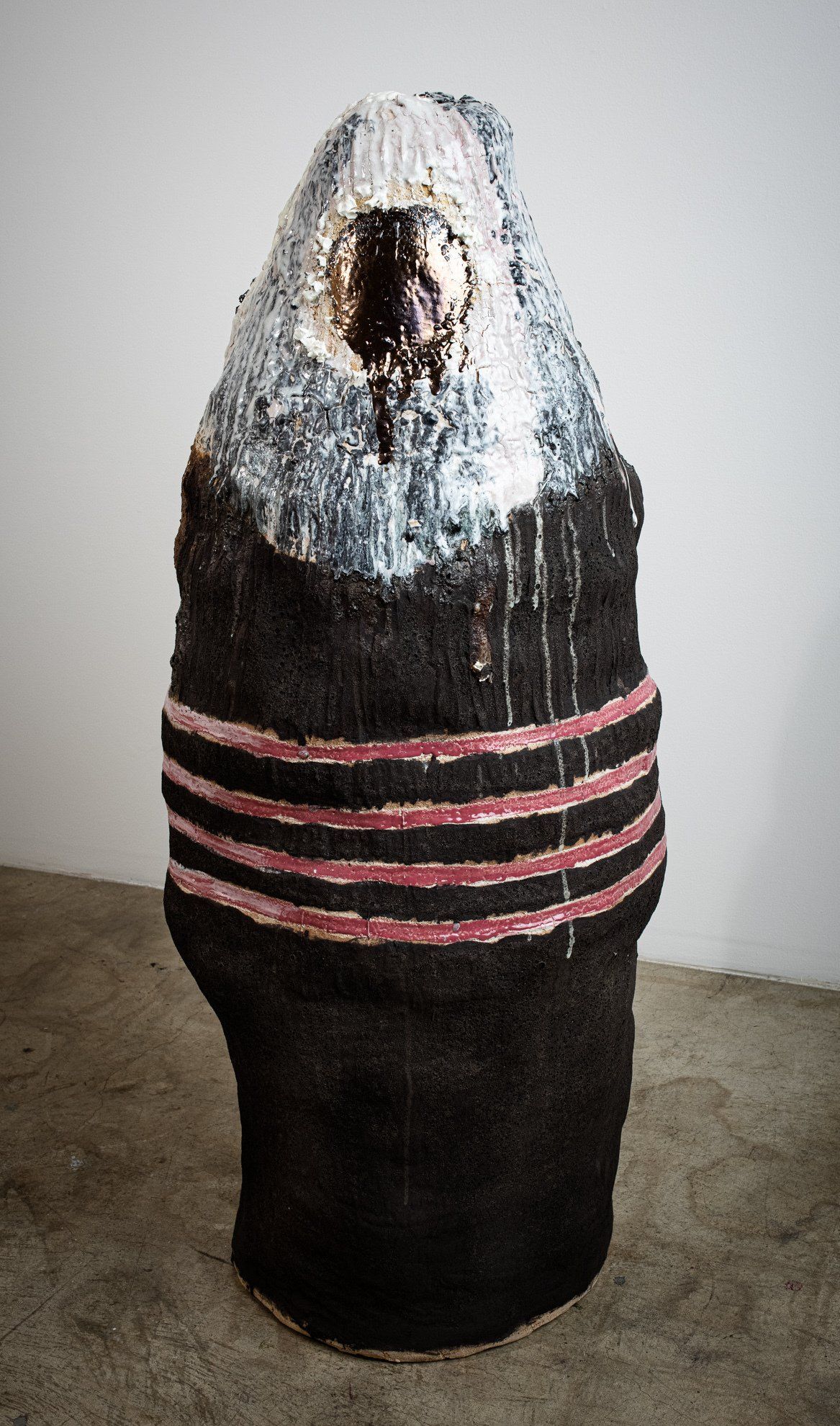 A statue of a person wrapped in a black and red striped blanket.