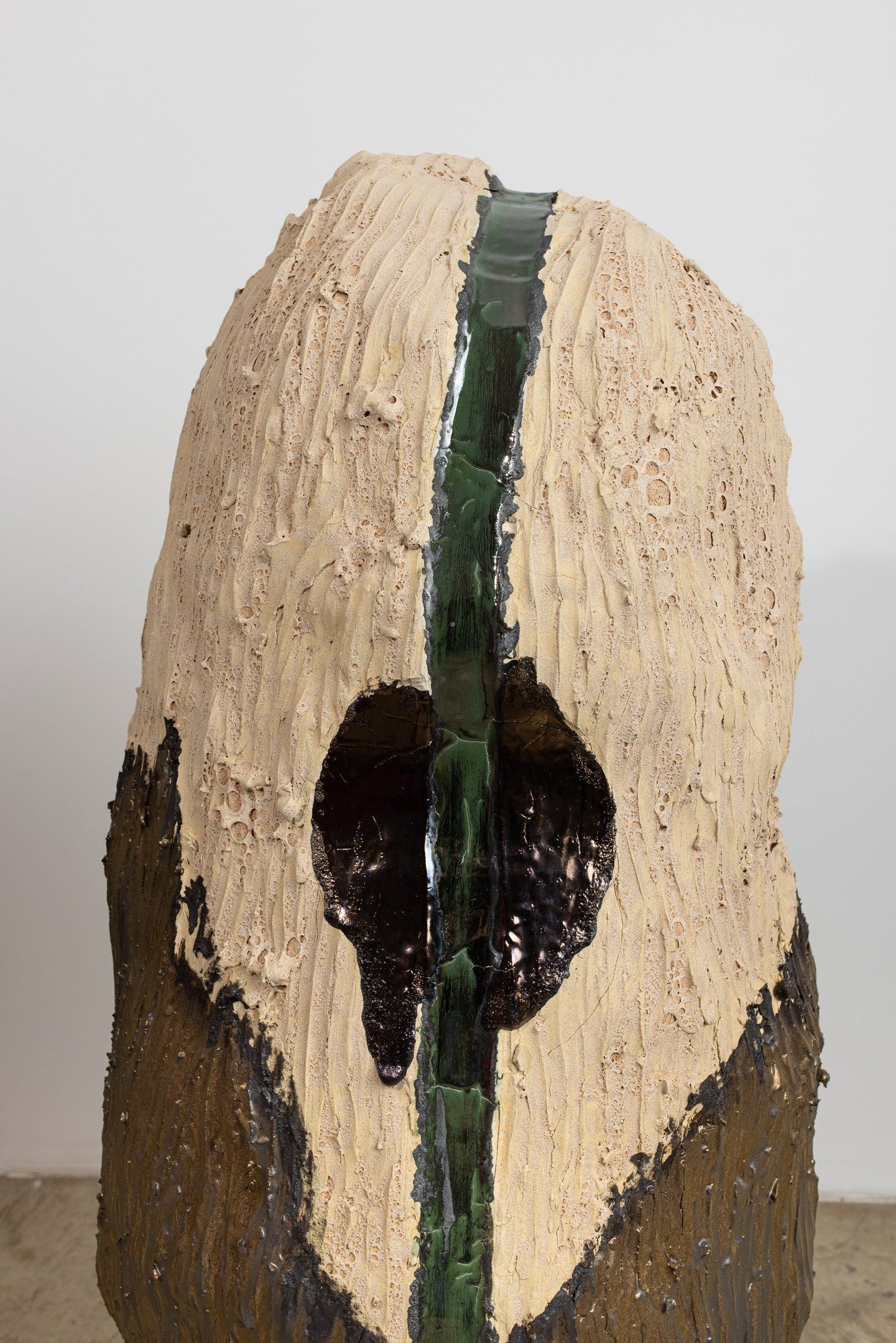 A ceramic sculpture with a green stripe on the side is sitting on a table.