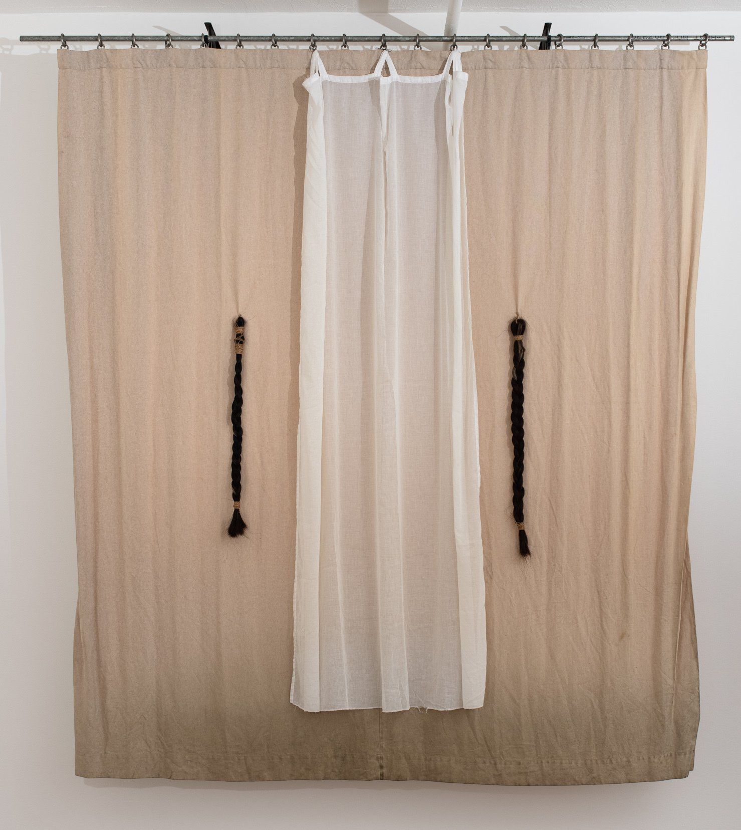 A white curtain is hanging on a white wall