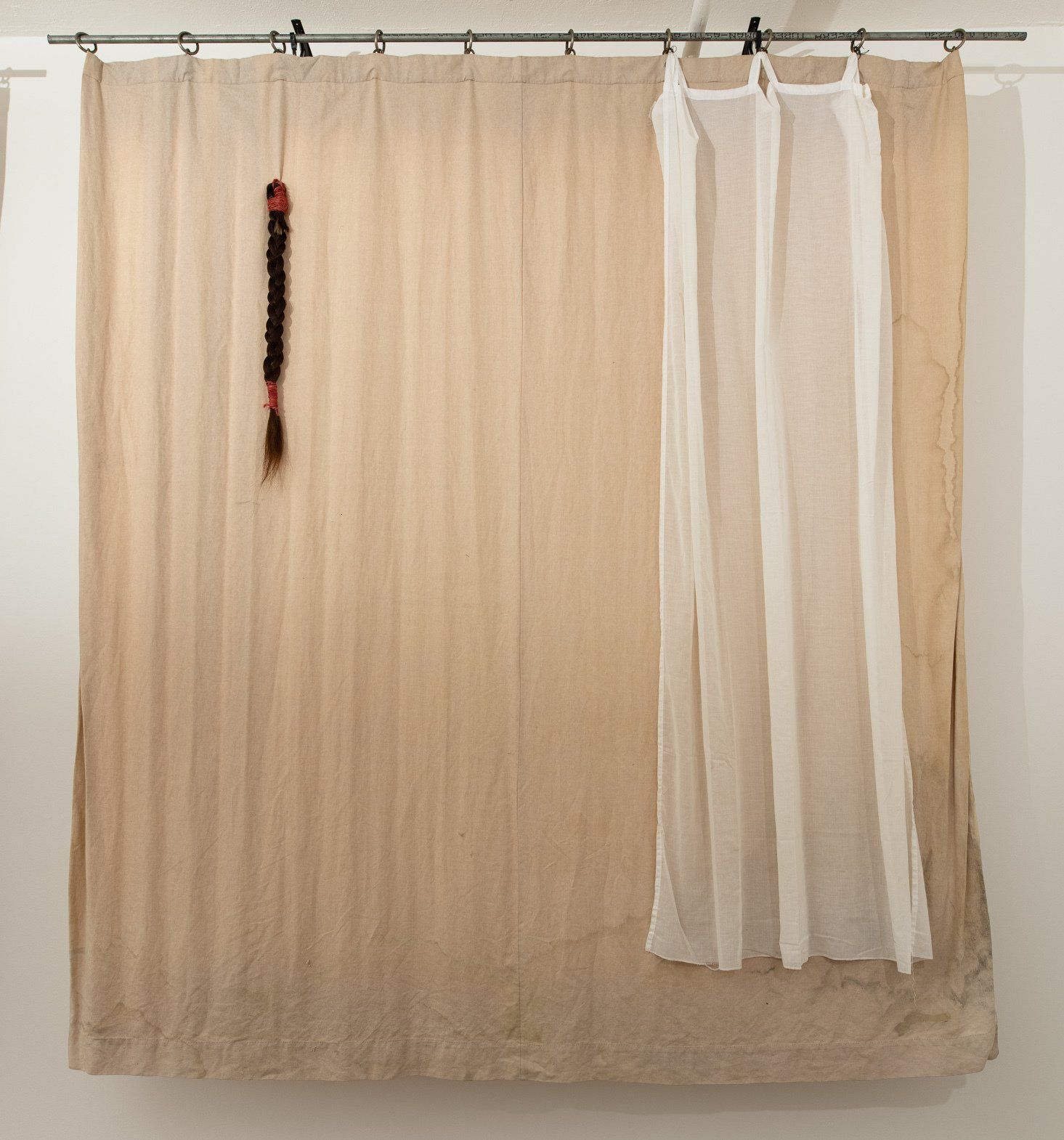 A curtain with a braid hanging from it and a white curtain