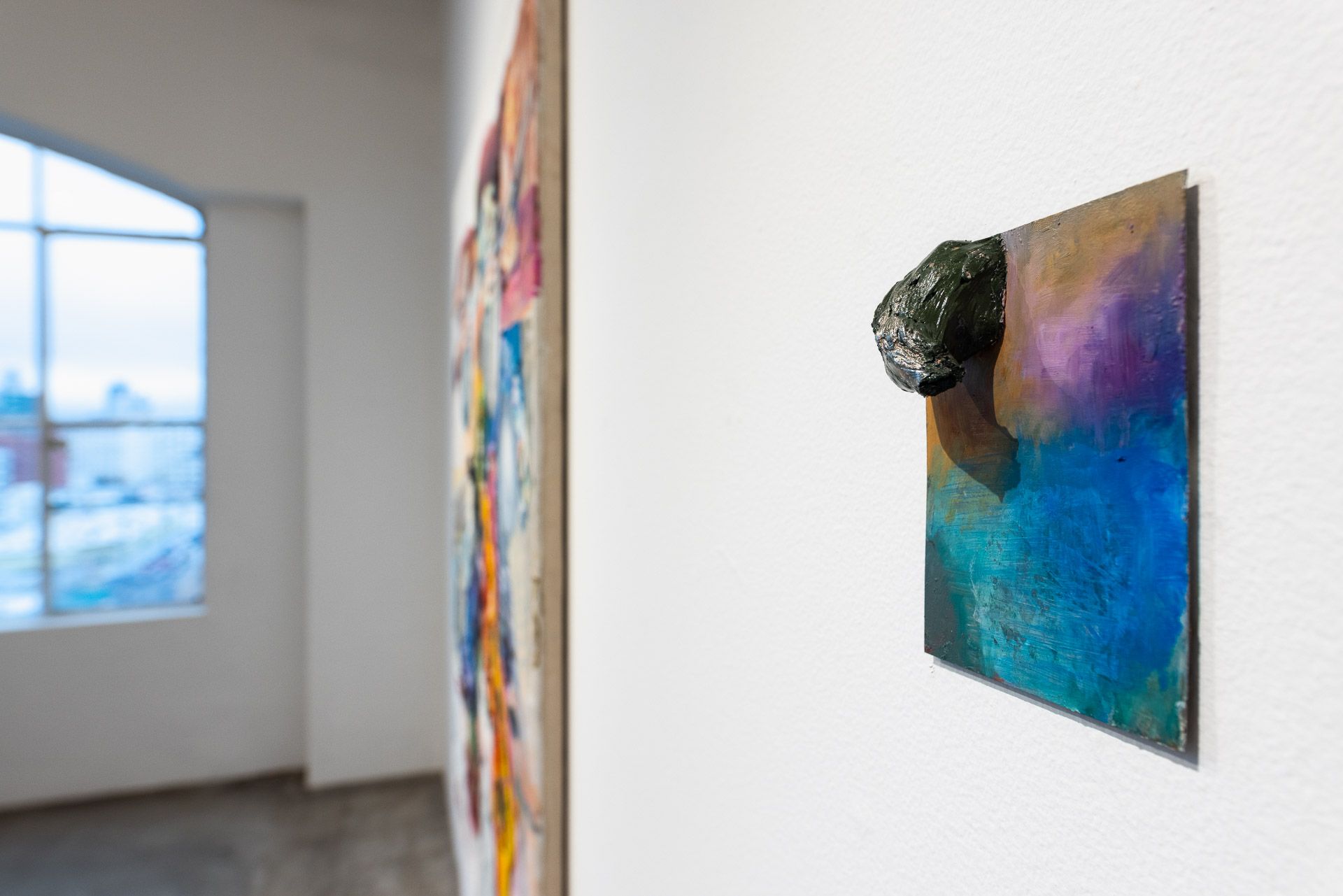 A painting is hanging on a wall in a room next to a window.