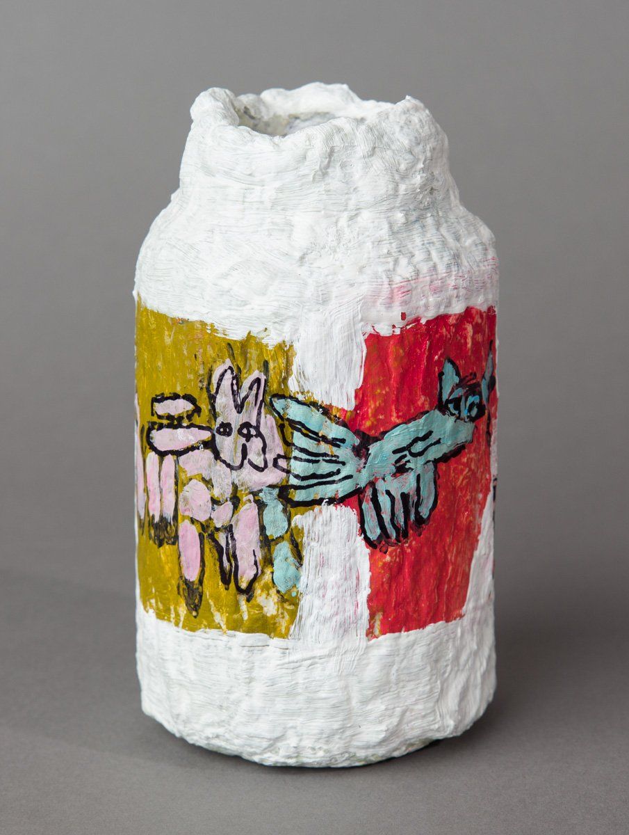 A white vase with a drawing on it is sitting on a table.