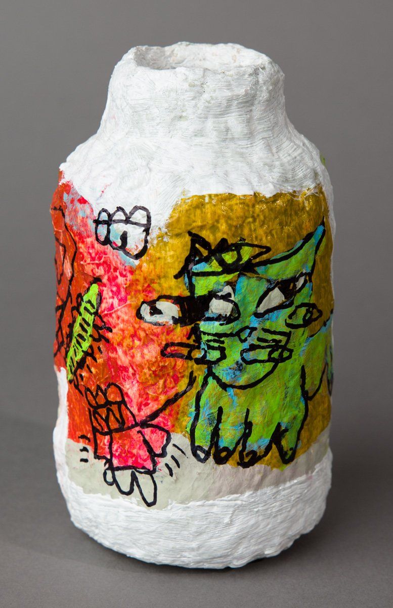 A white vase with a colorful drawing on it.