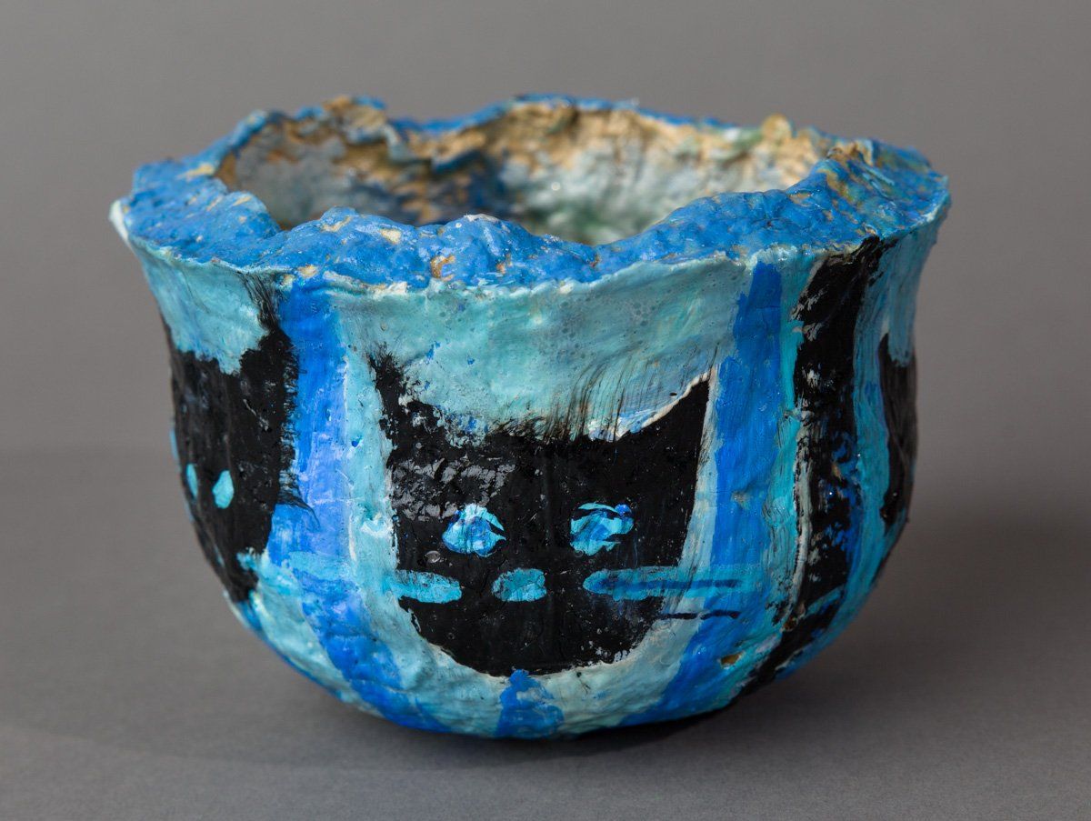 A blue and black bowl with a black cat on it.