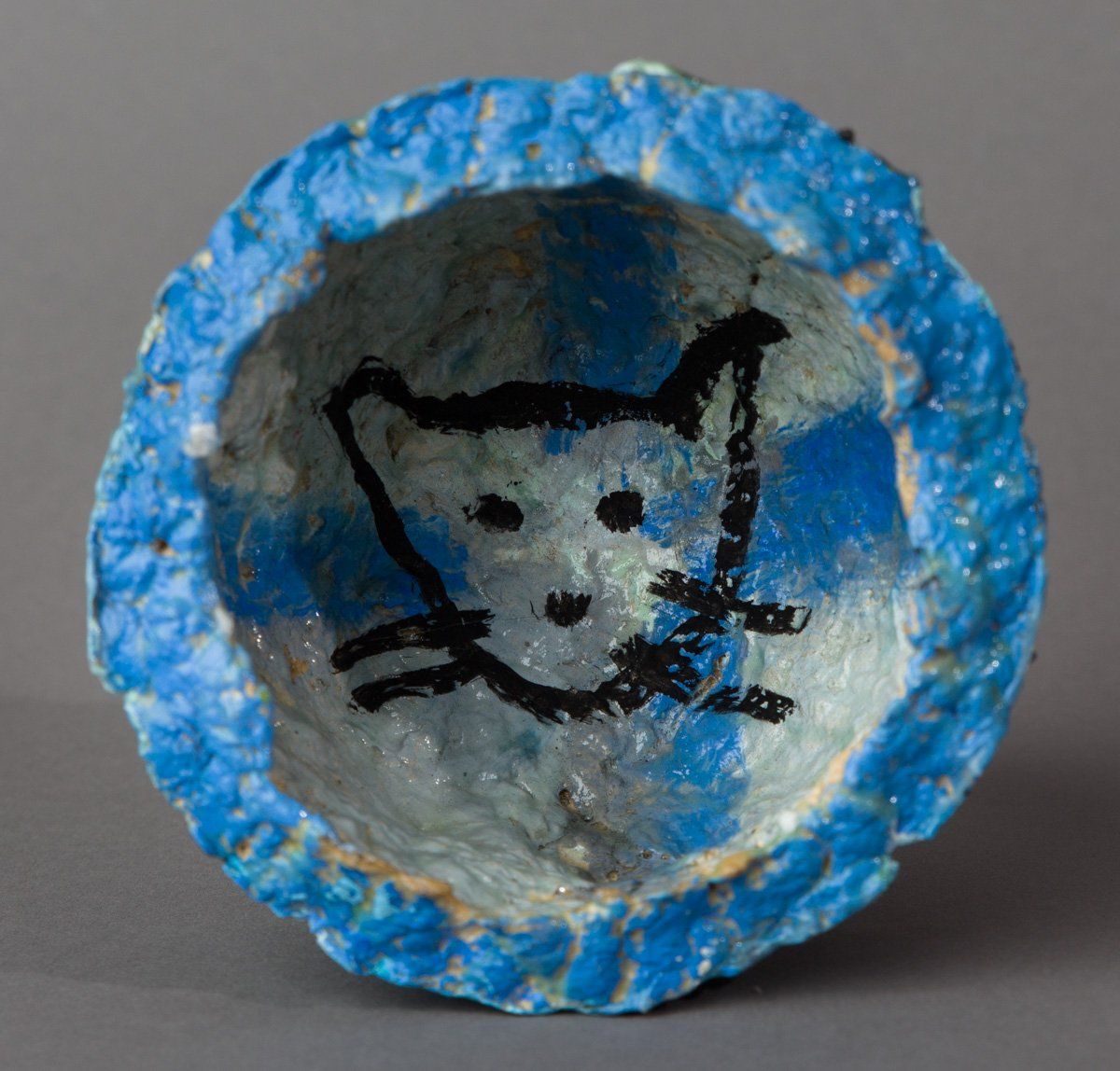 A blue and white bowl with a drawing of a cat on it