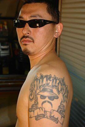 A shirtless man with sunglasses and a tattoo on his arm