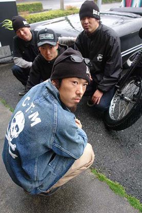 A group of men are squatting next to a motorcycle.