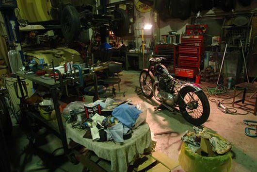 A motorcycle is parked in a messy garage.