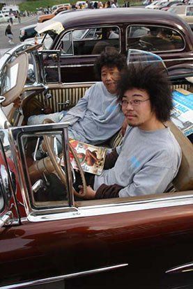 Two men with curly hair are sitting in a car.