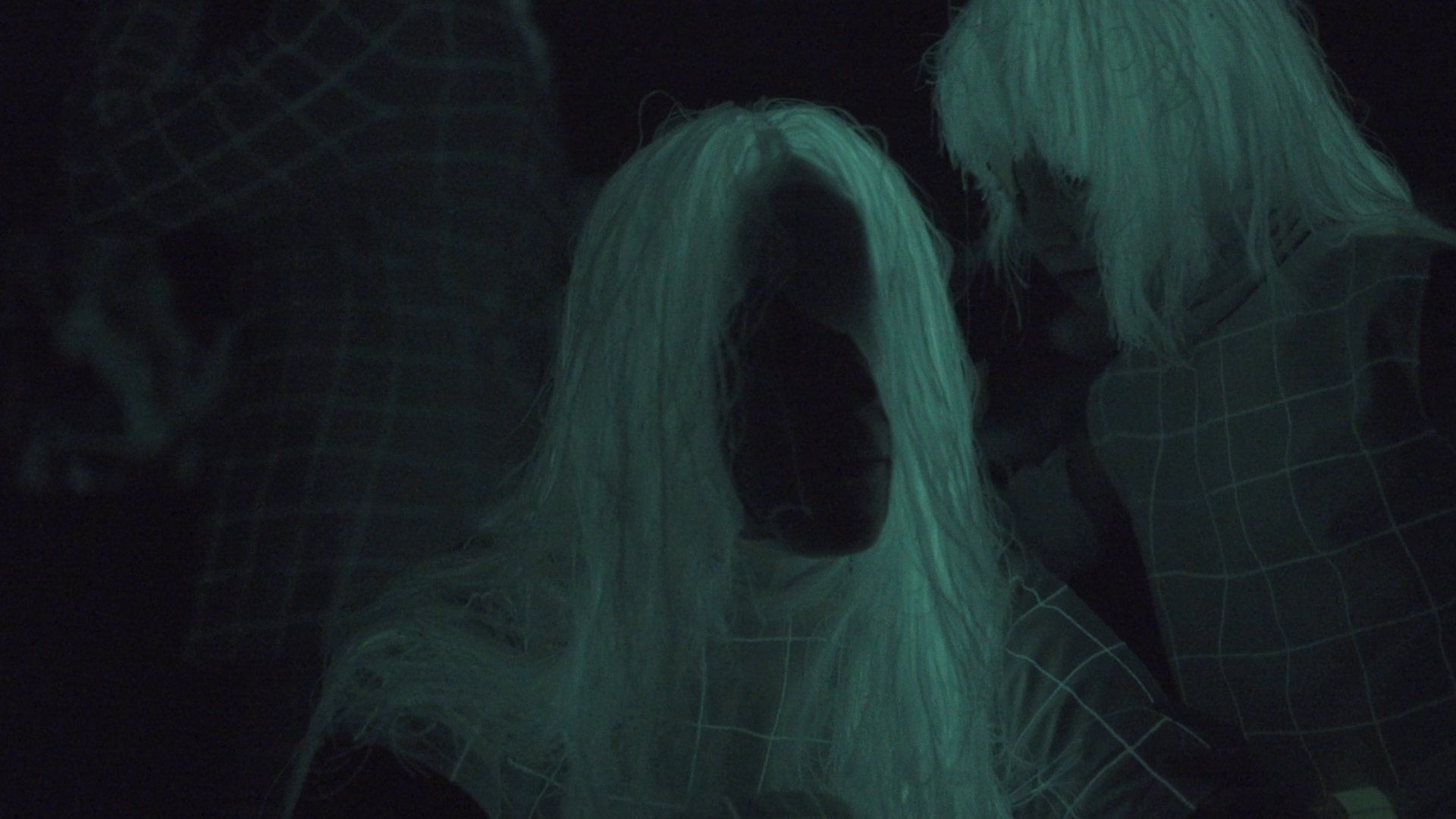 A woman with long white hair is glowing in the dark.