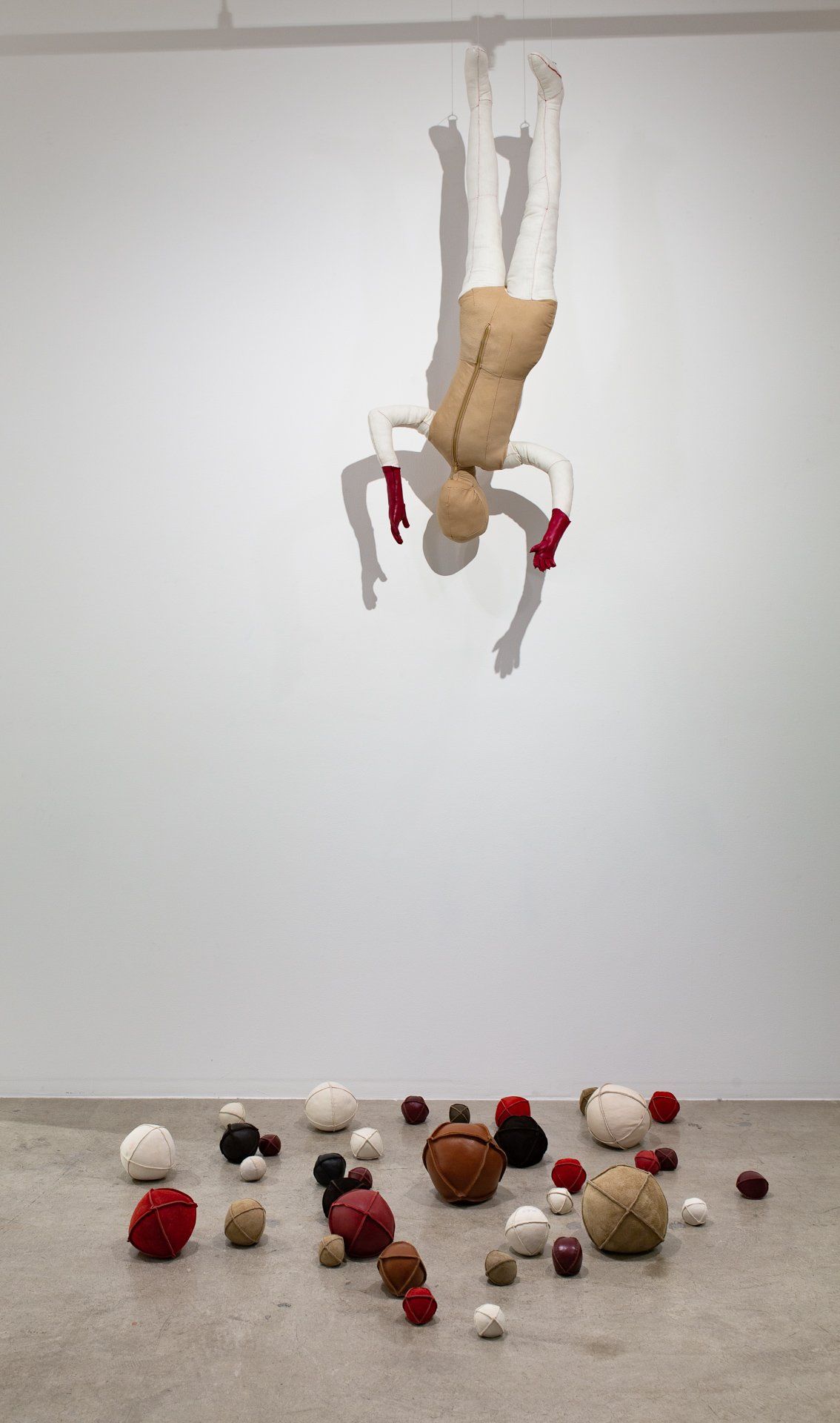 A sculpture of a person hanging down over a white background.