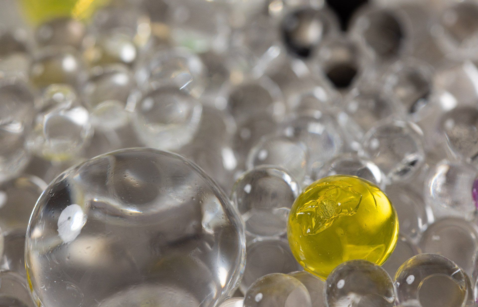 There is a yellow ball in the middle of a pile of clear balls.