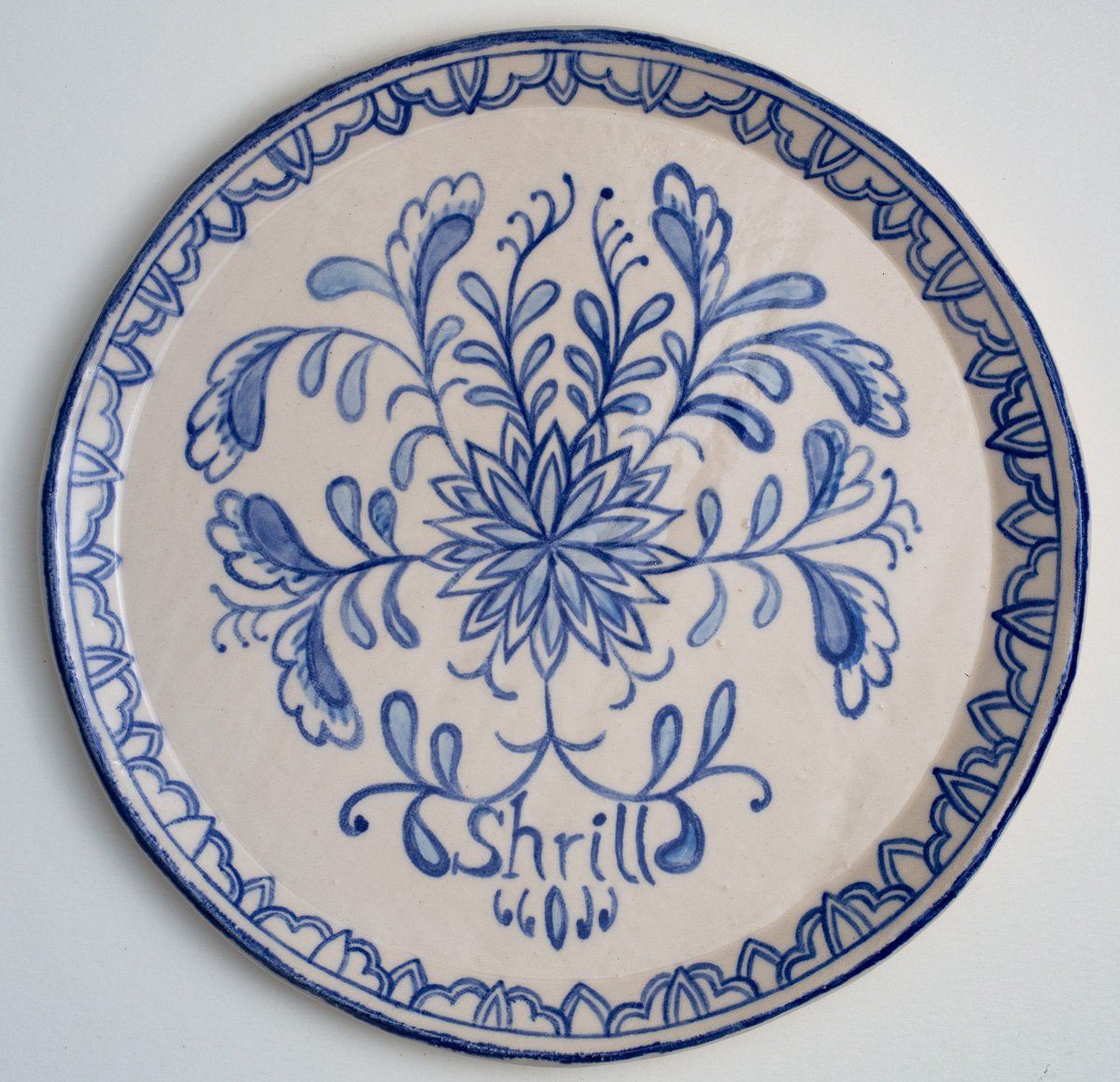 A blue and white plate with the word shrill on it