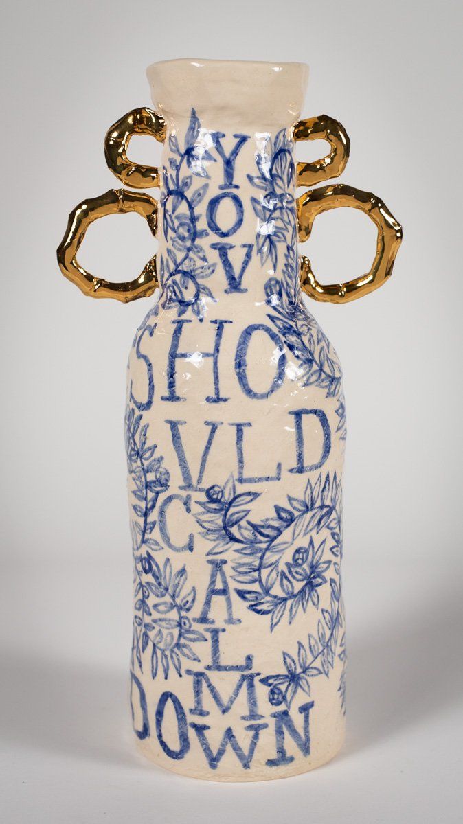 A blue and white vase with gold handles that says you should calm down