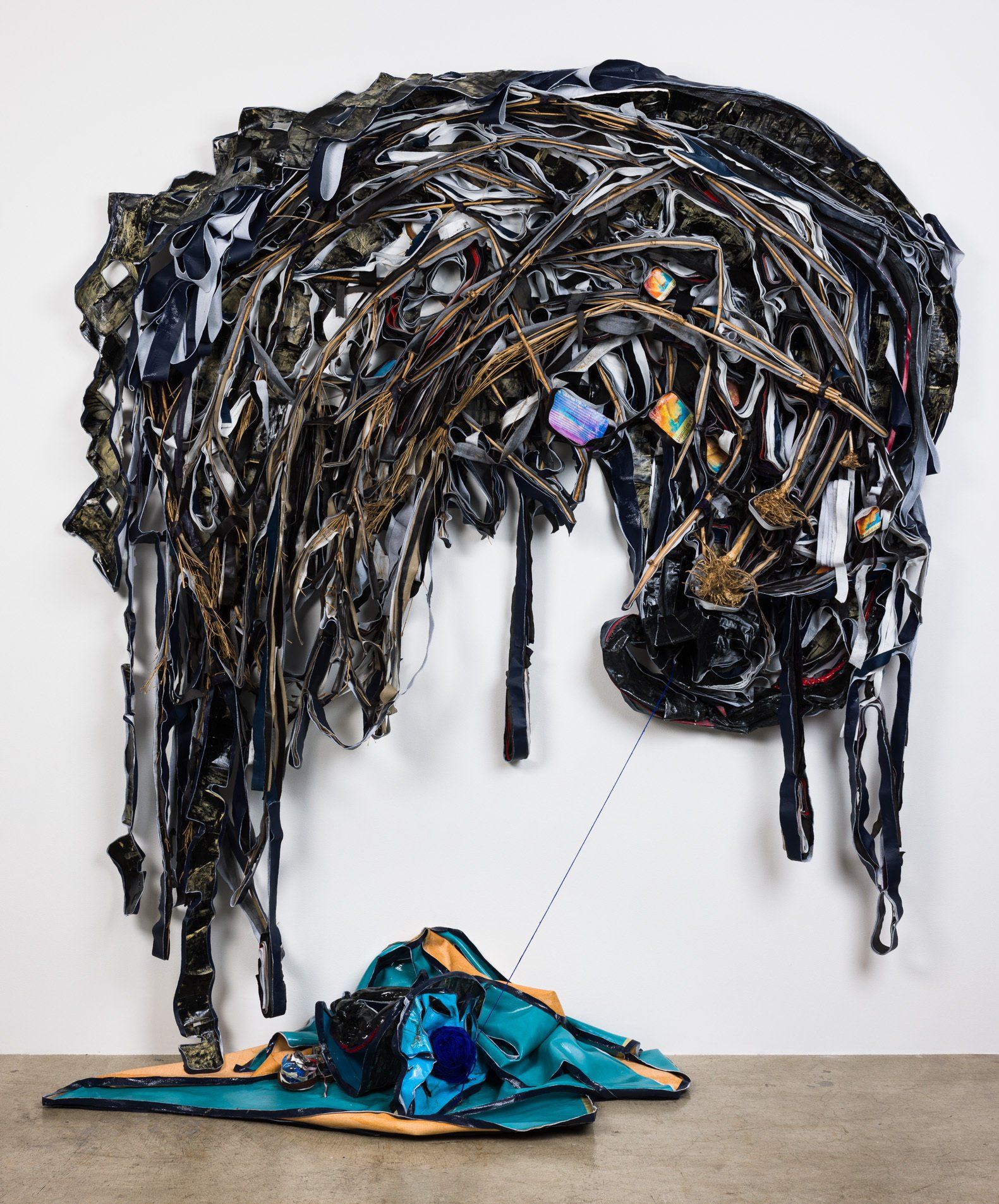 A large sculpture made out of clothes is hanging on a wall.