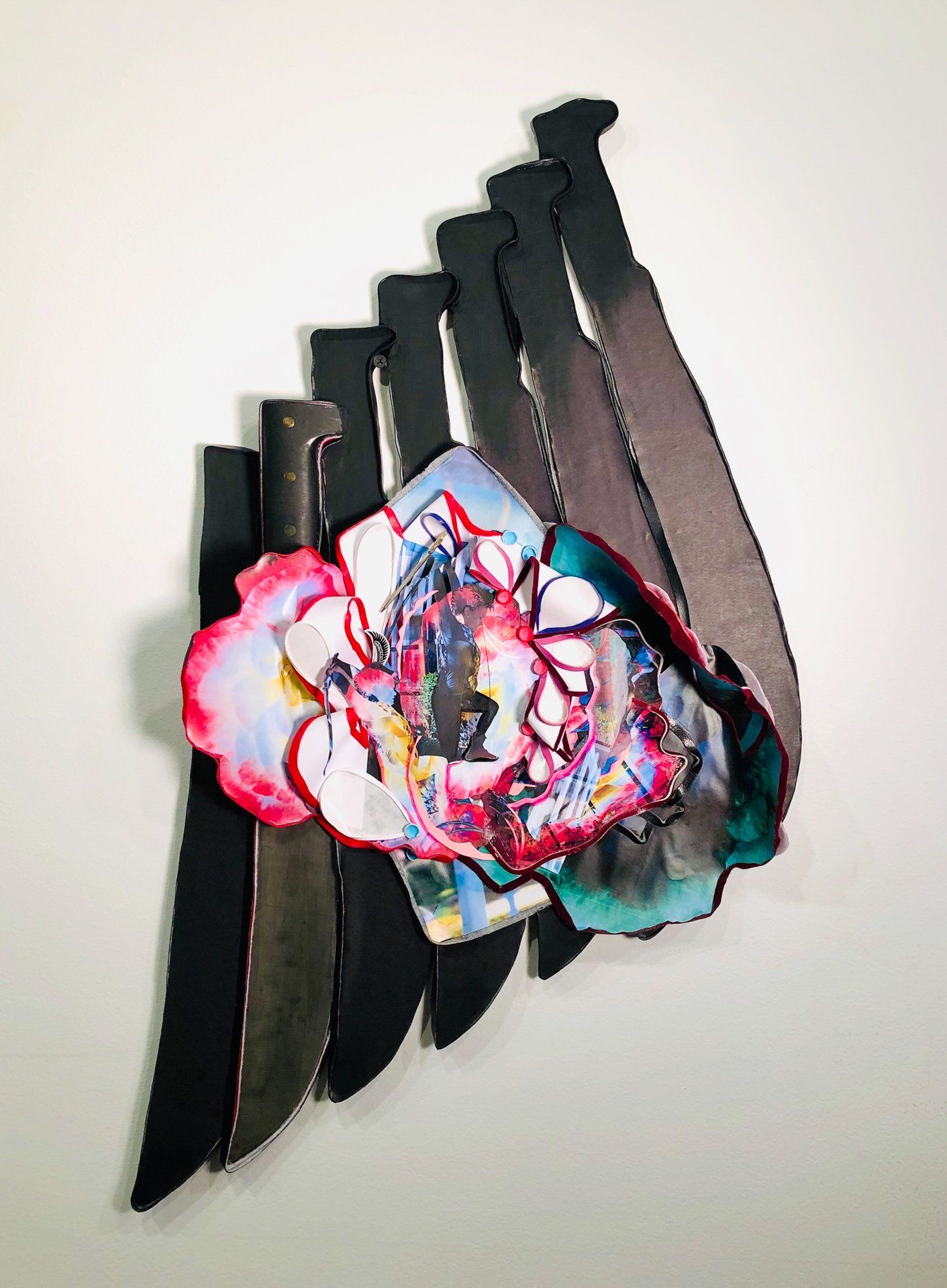 A painting of a flower made out of knives on a wall.