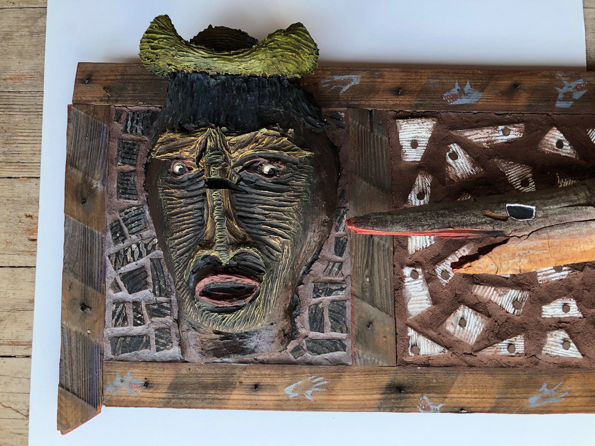 A wooden sculpture of a man 's face with a crown on top