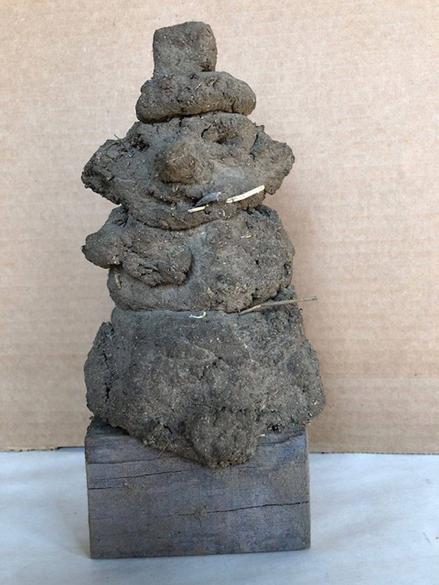 A statue of a snowman made of dirt is sitting on a table.