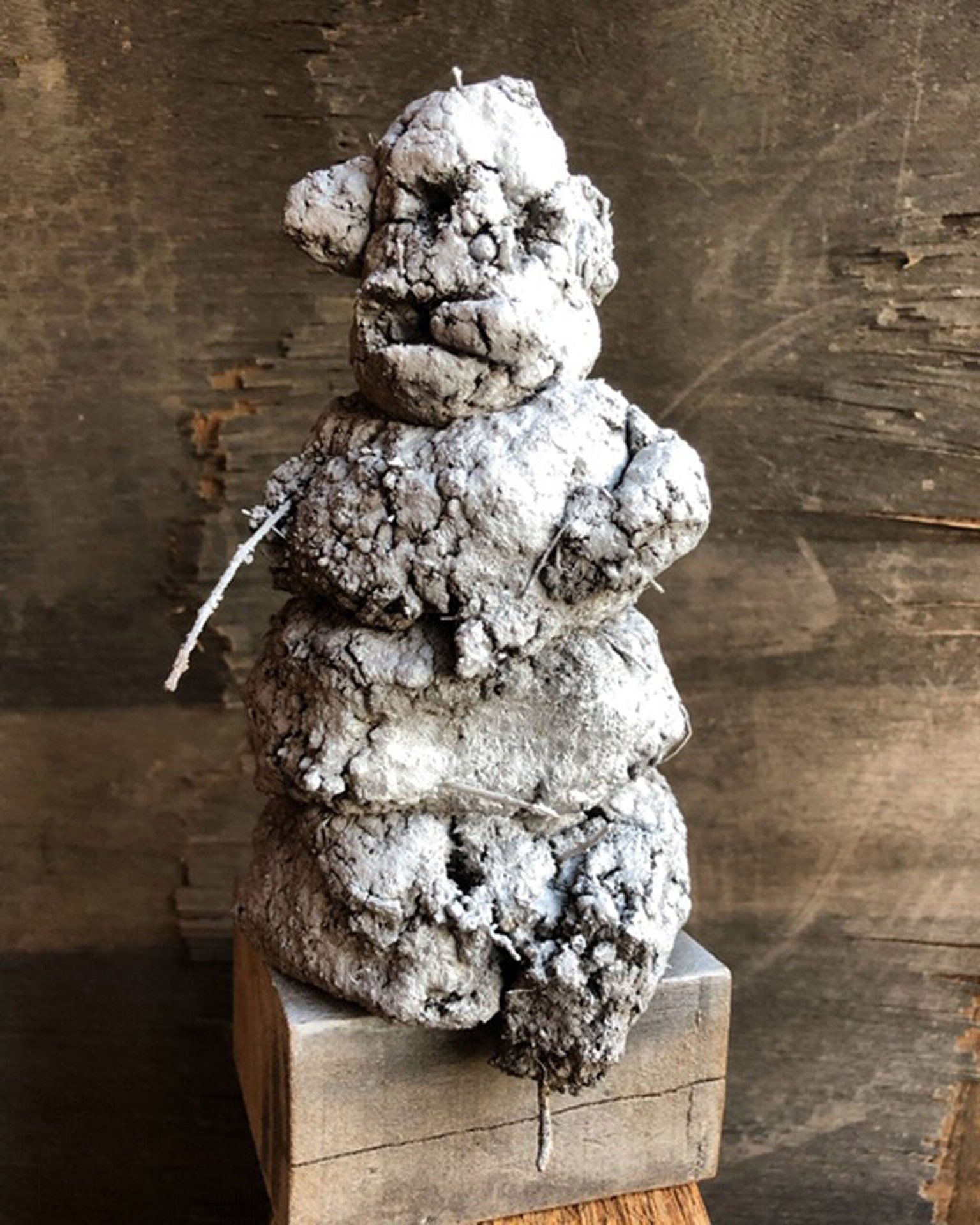 A statue of a person sitting on top of a wooden block.