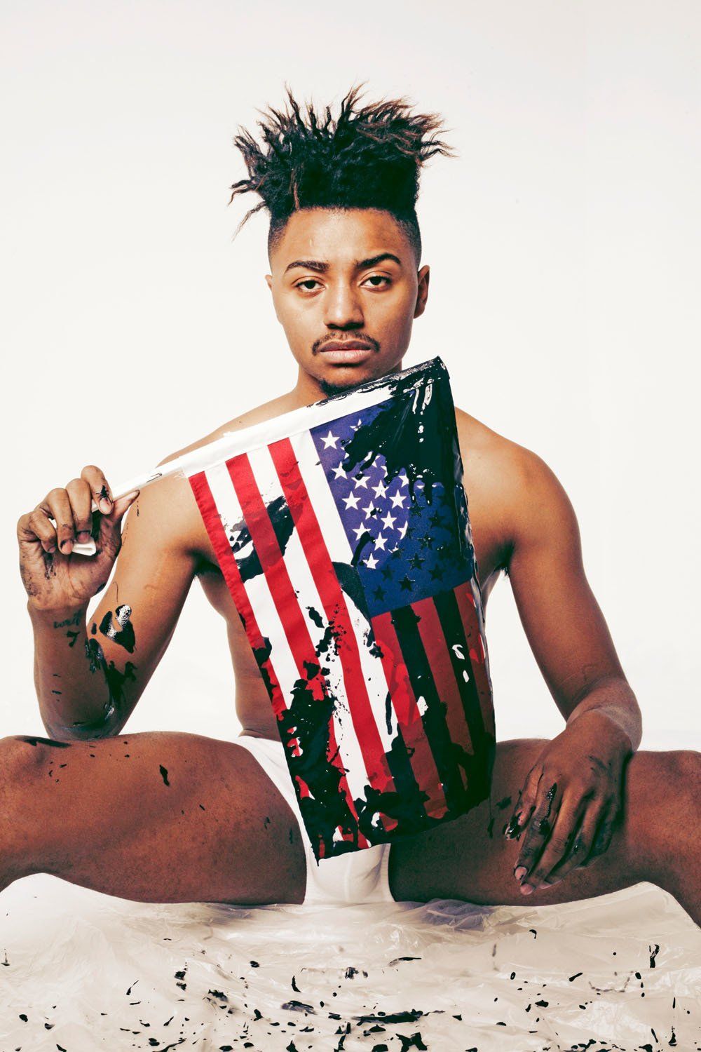 A shirtless man is holding an american flag in his hand