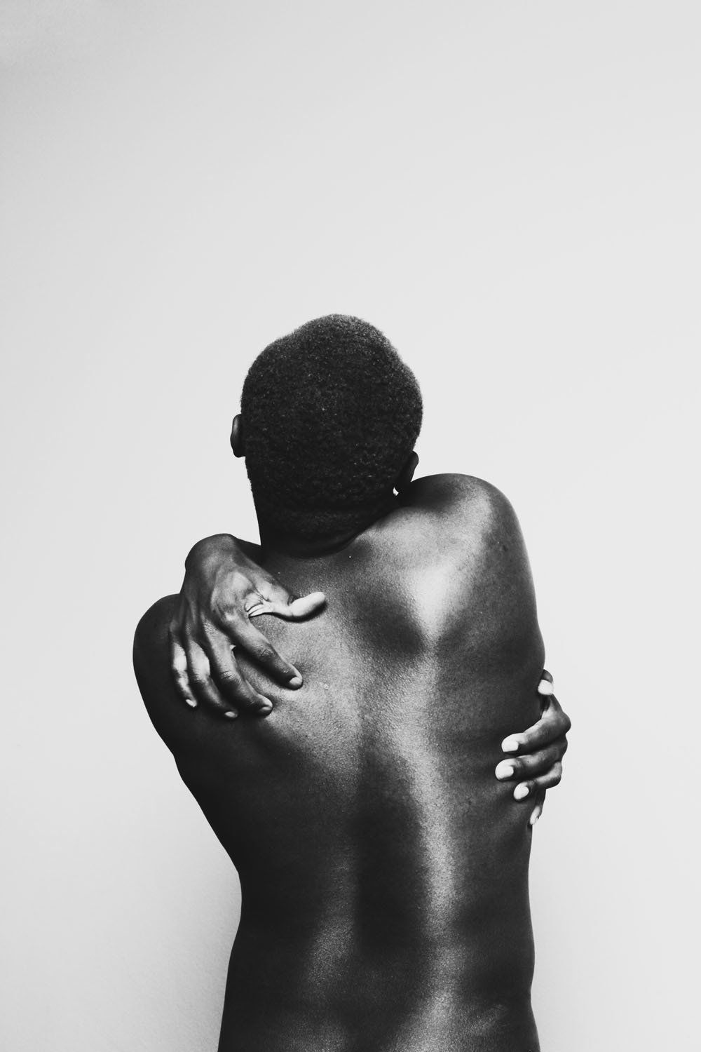 A black and white photo of a man hugging his back.