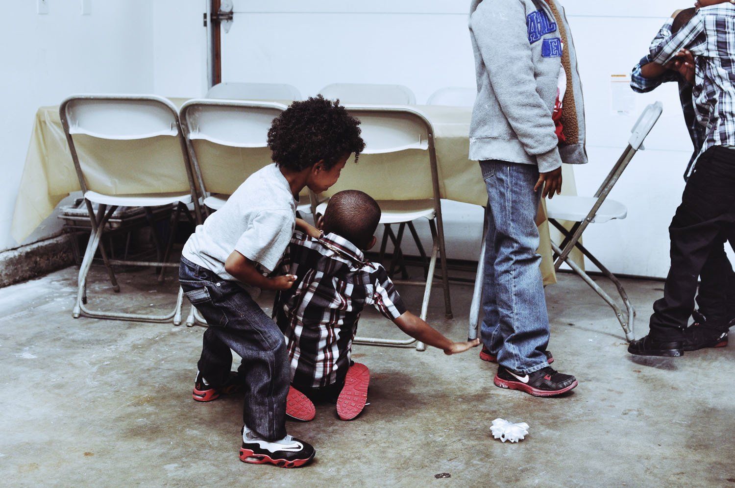 A group of children are playing in a room with folding chairs