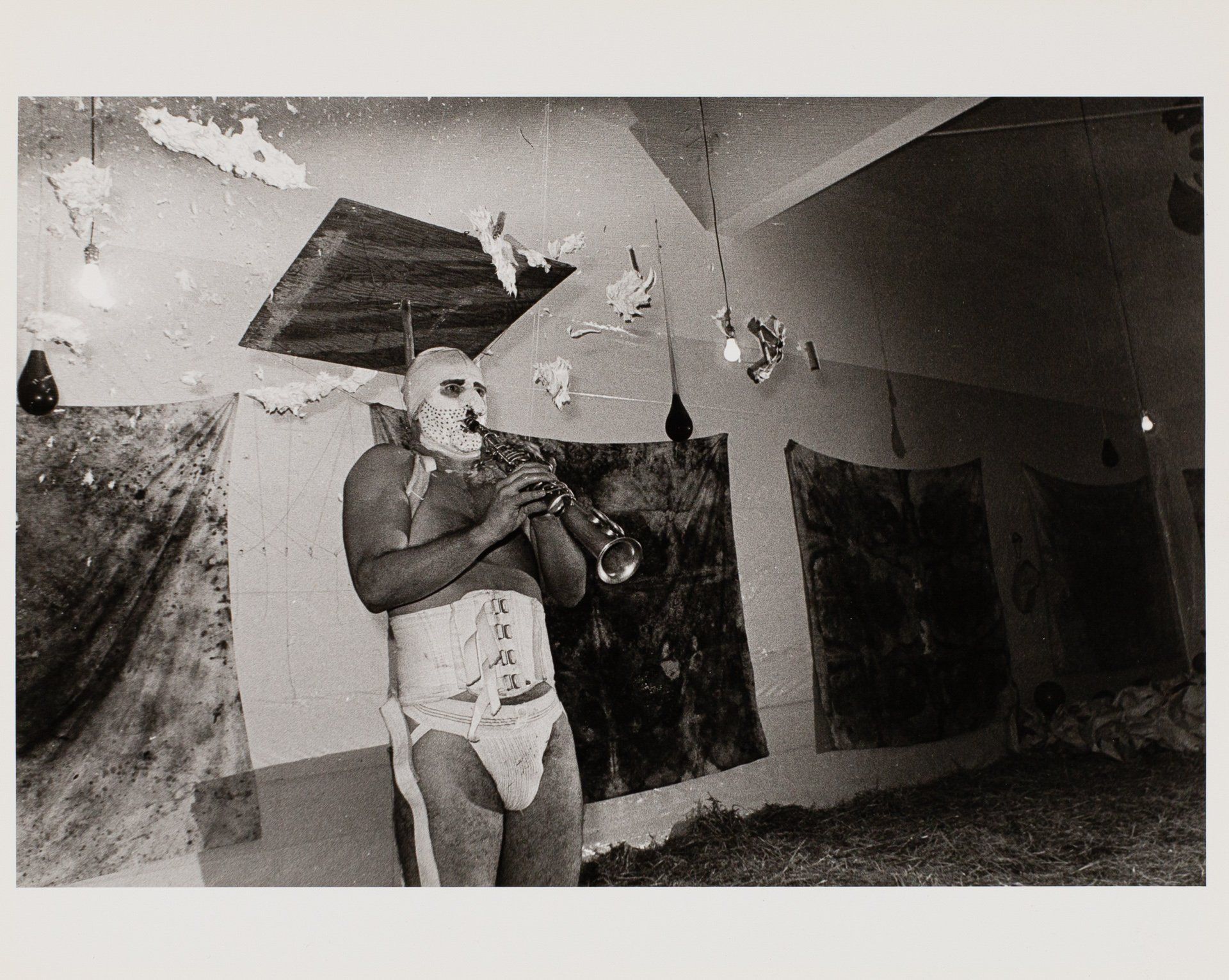 A man in a mask is playing a trumpet in a room.
