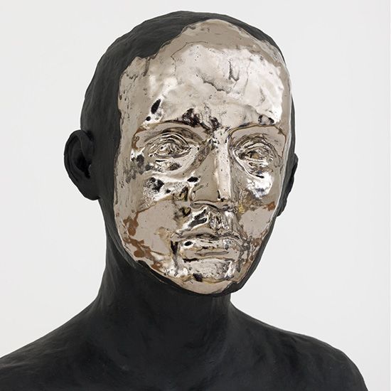 A statue of a man with a silver mask on his face