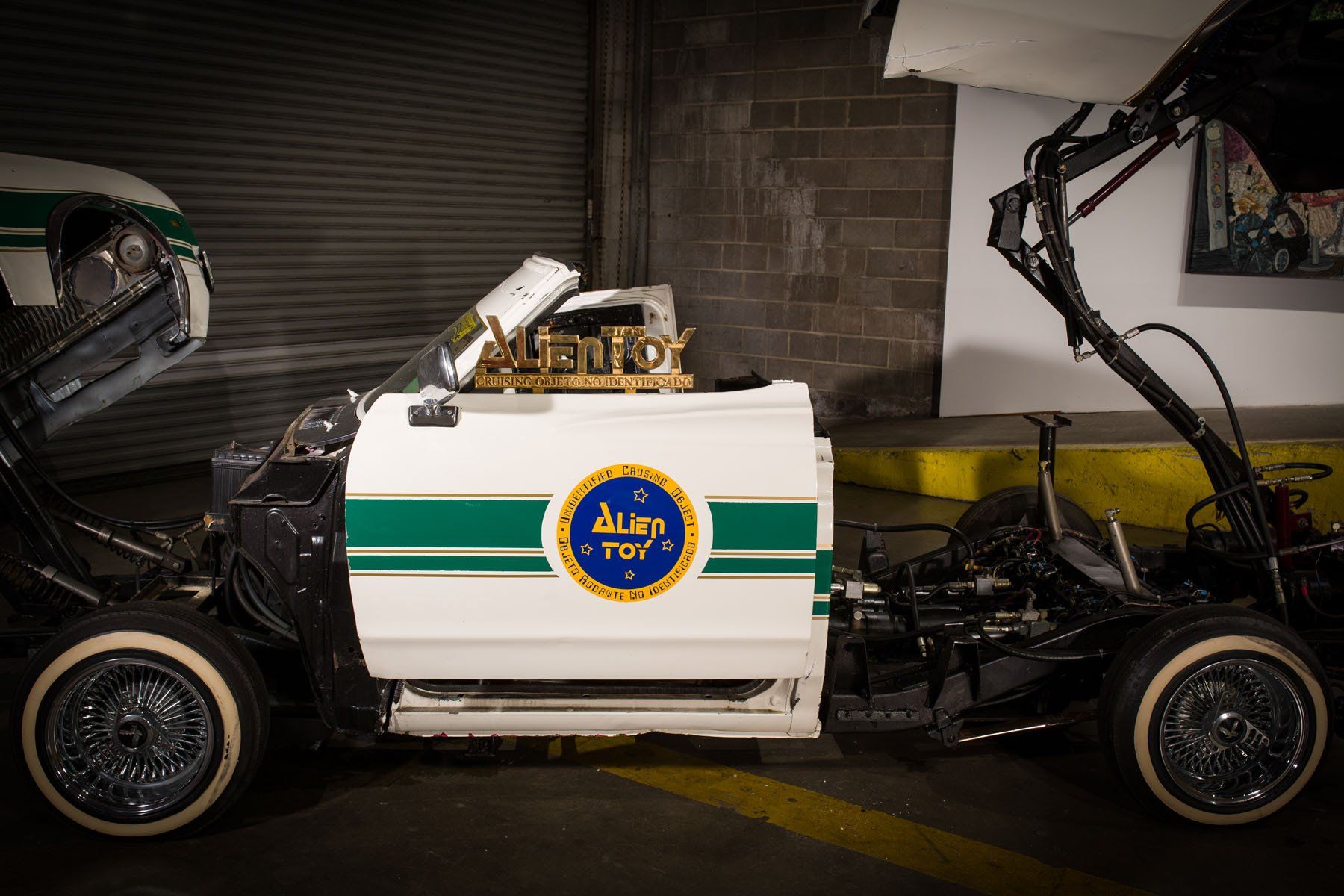 A white car with a green stripe on the side is parked in a garage.