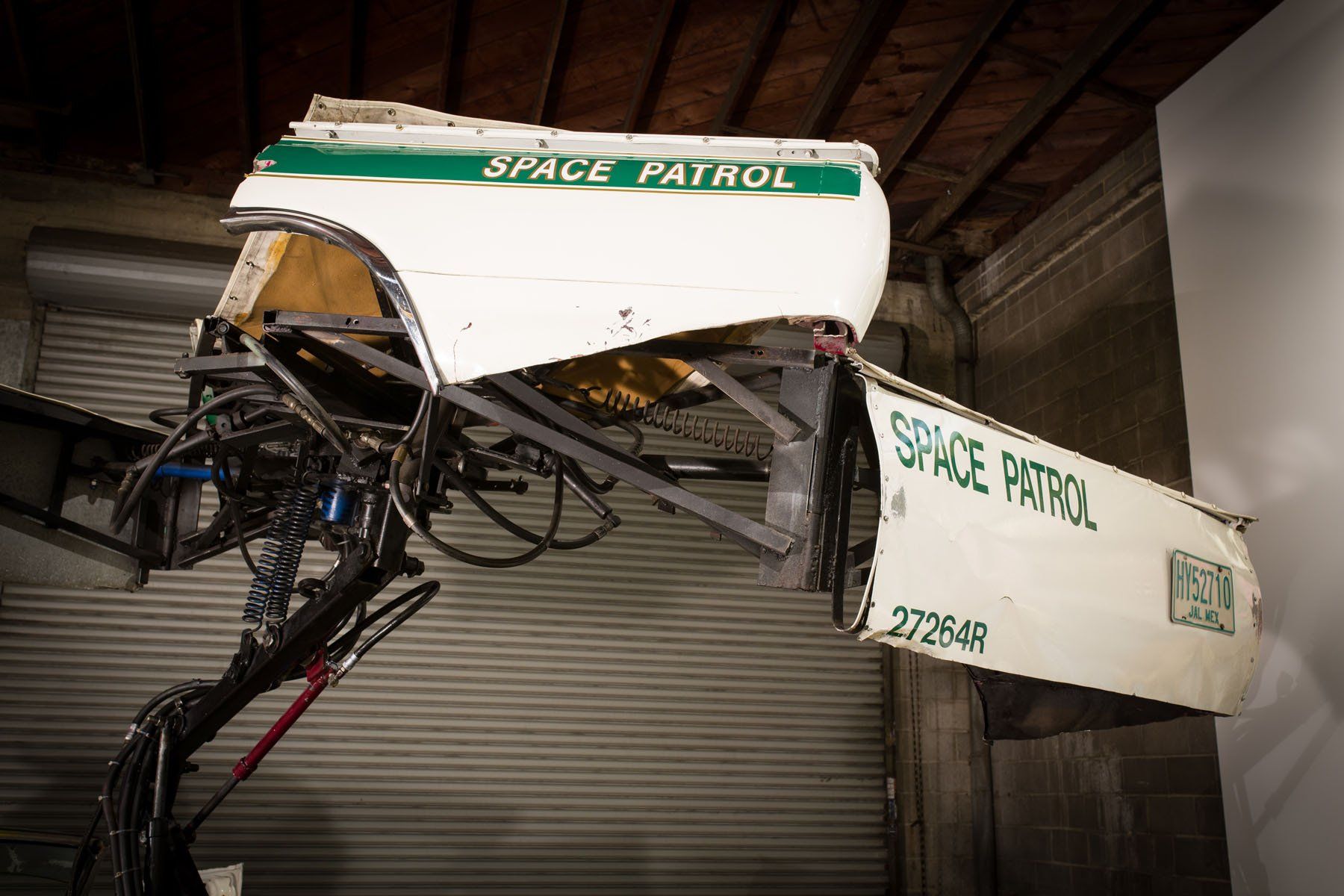 A space patrol vehicle is hanging from the ceiling in a garage.