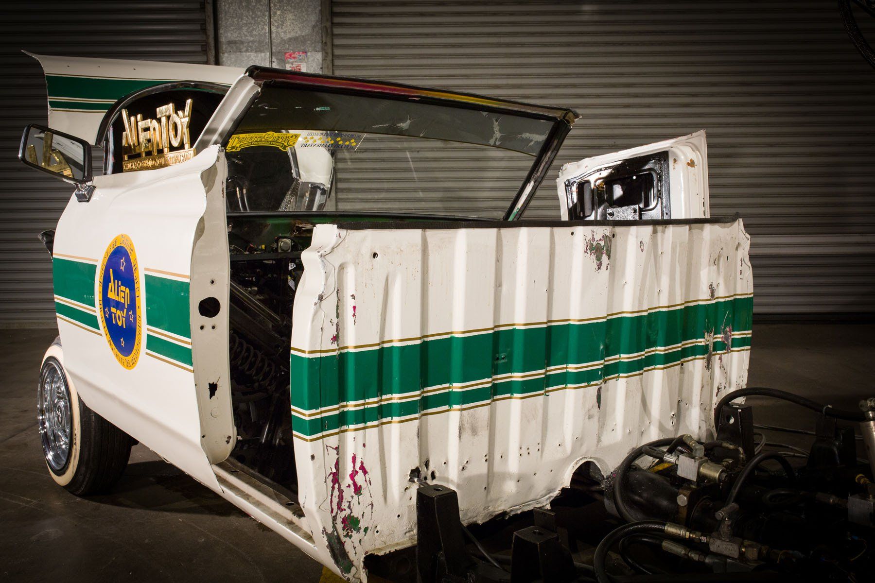 A white car with green stripes on the side is parked in a garage.