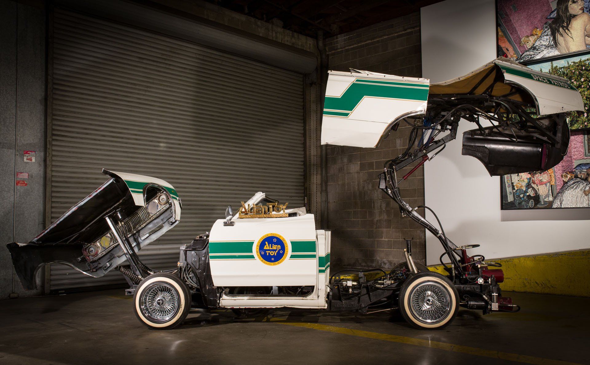 A white and green police car is sitting in a garage.