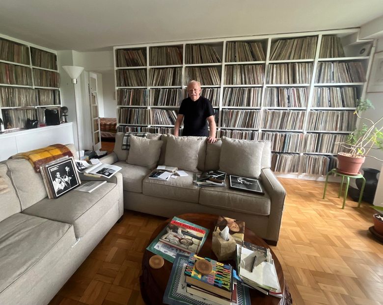 Man in a living room surrounded by lp records.