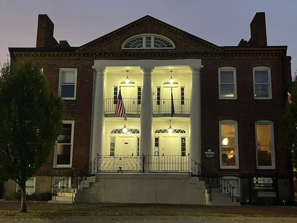 A man in a suit and tie is smiling in front of a window
