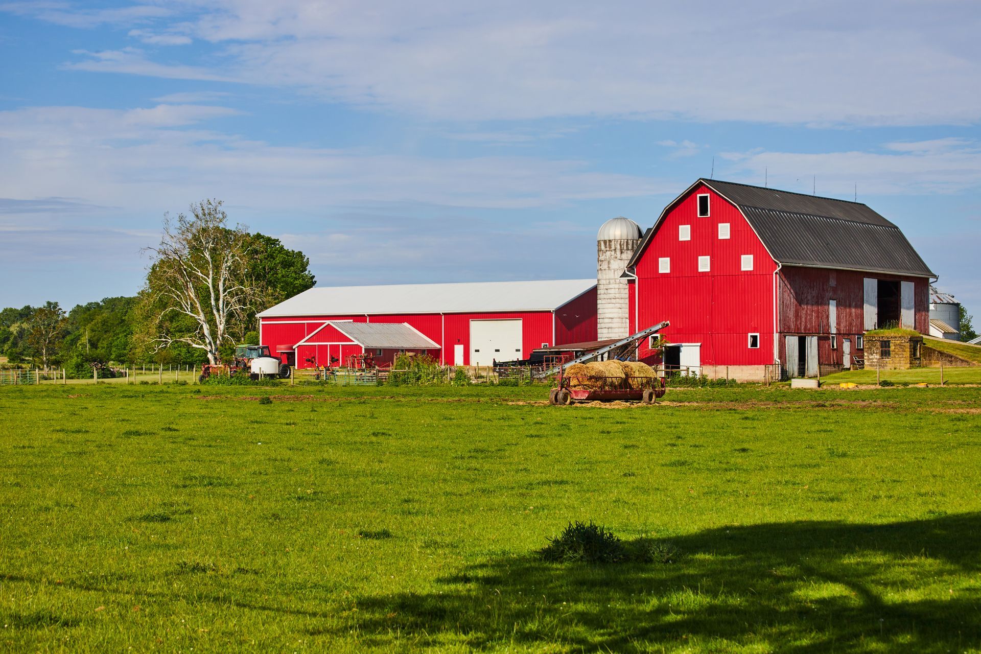 A woman is carrying a little girl on her shoulders in a field at sunset.
