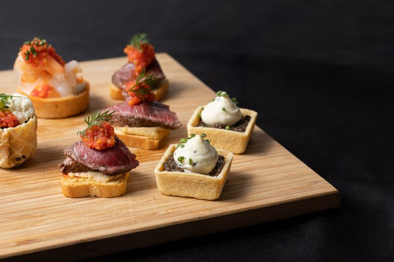 A wooden cutting board topped with a variety of appetizers.