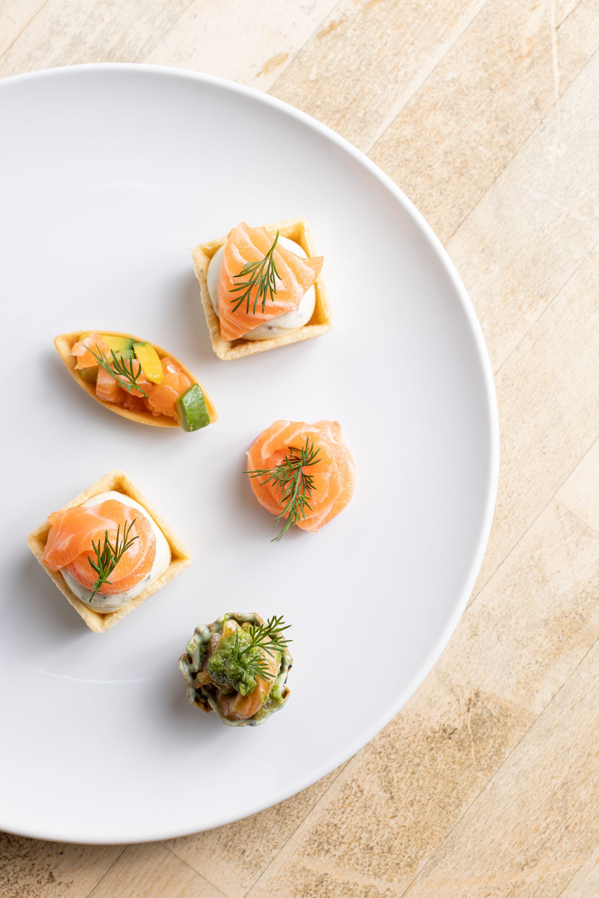 A white plate topped with a variety of appetizers on a wooden table.