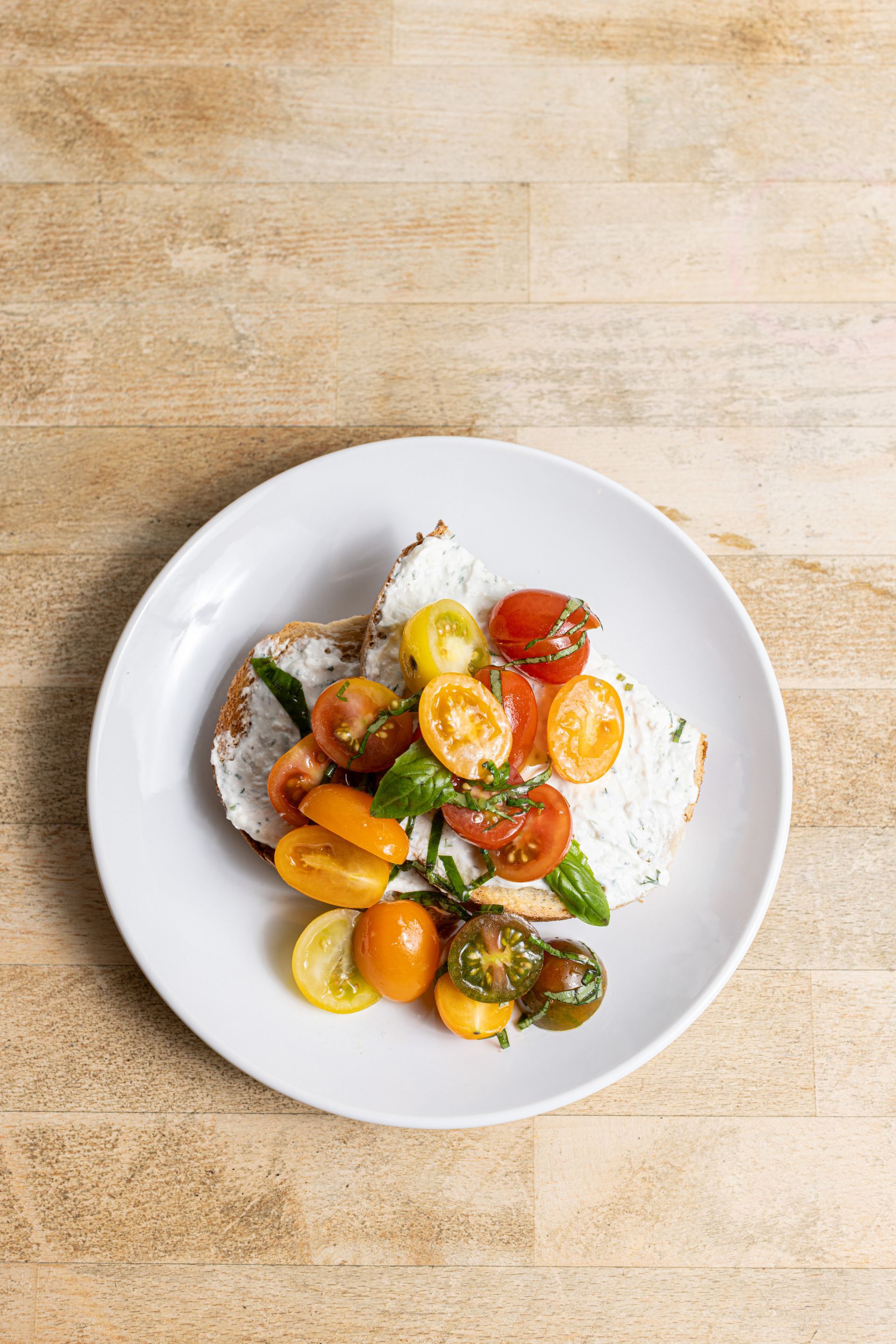 A white plate topped with tomatoes and bread on a wooden table.