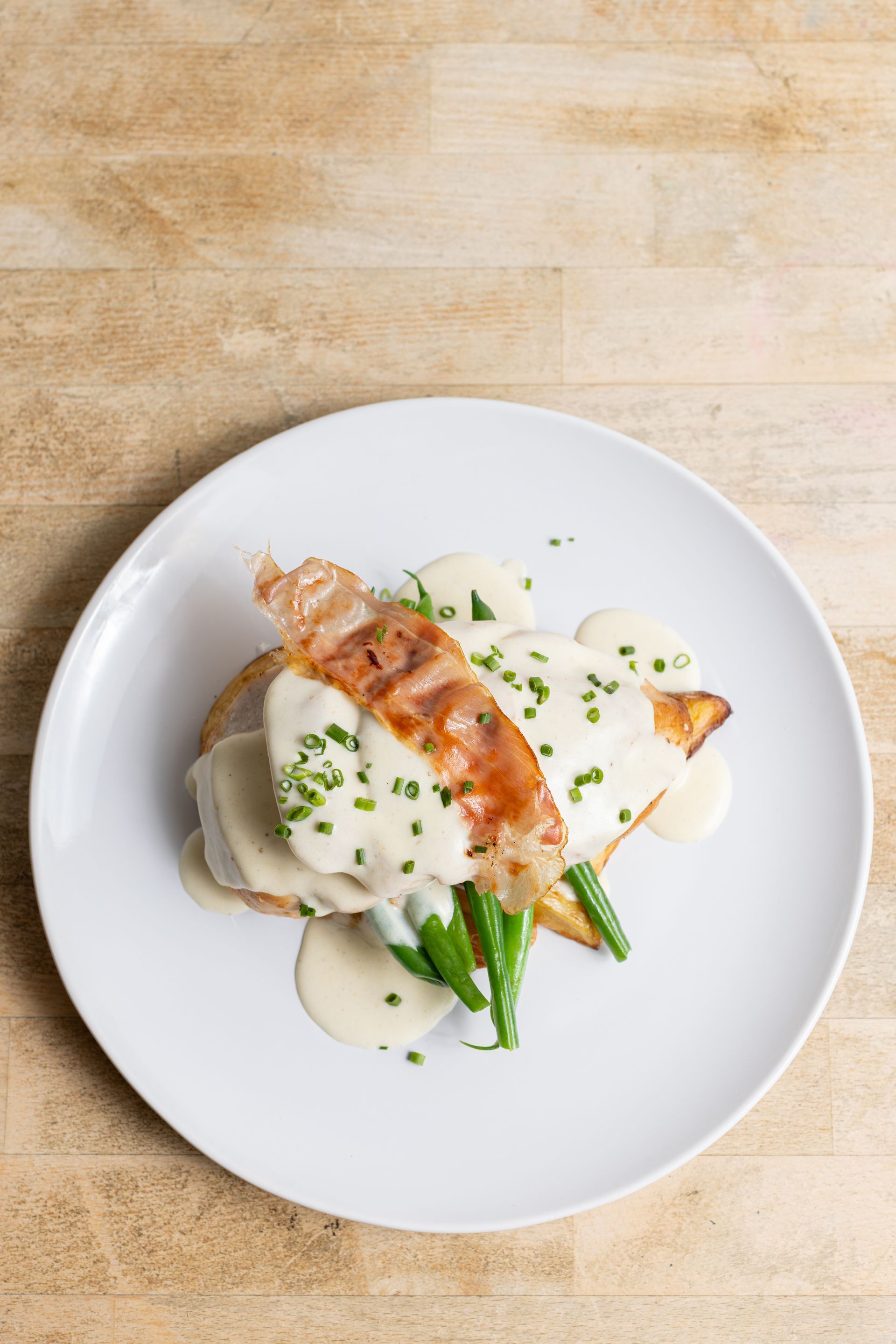A white plate topped with a piece of food on a wooden table.