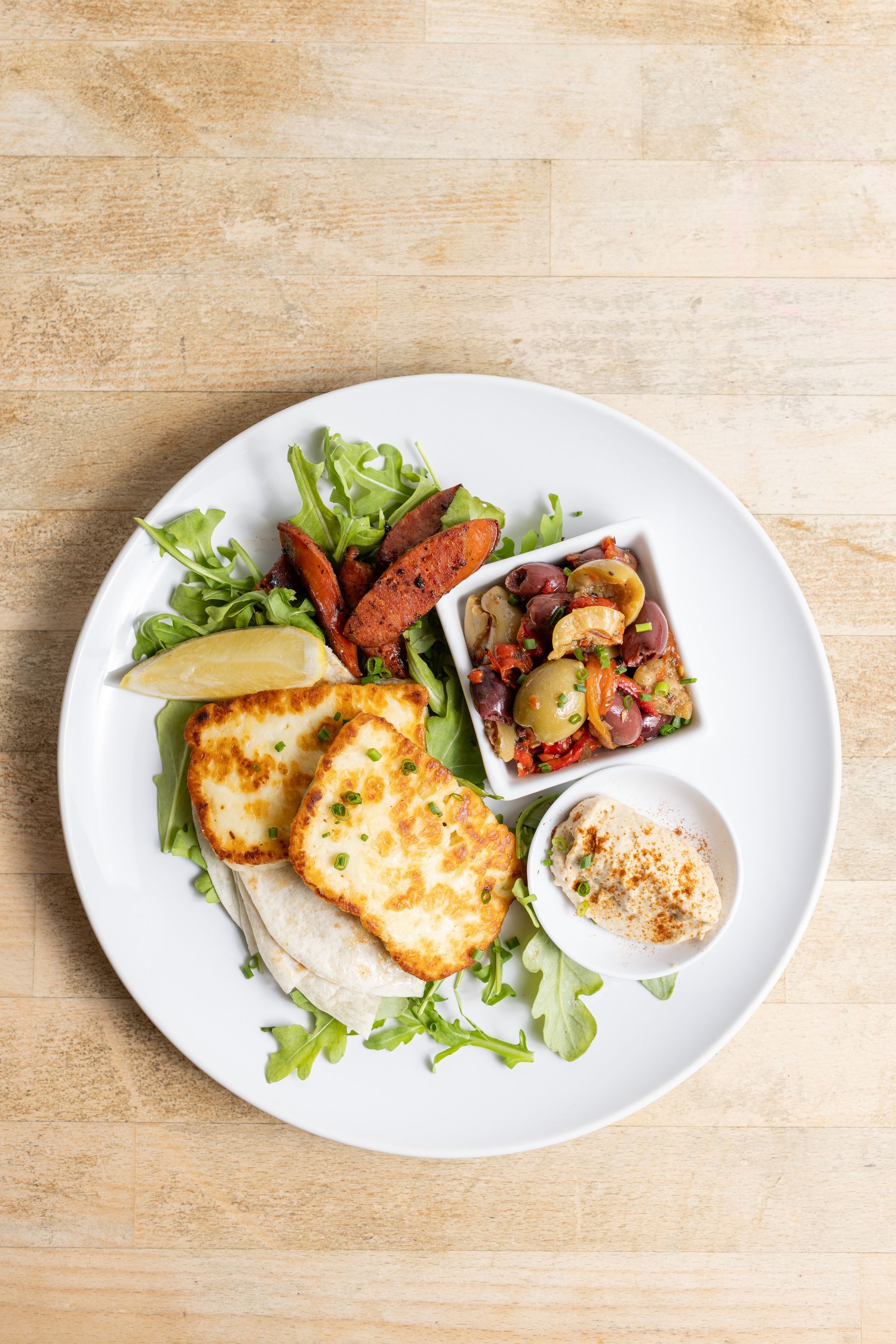 A white plate topped with a variety of food on a wooden table.