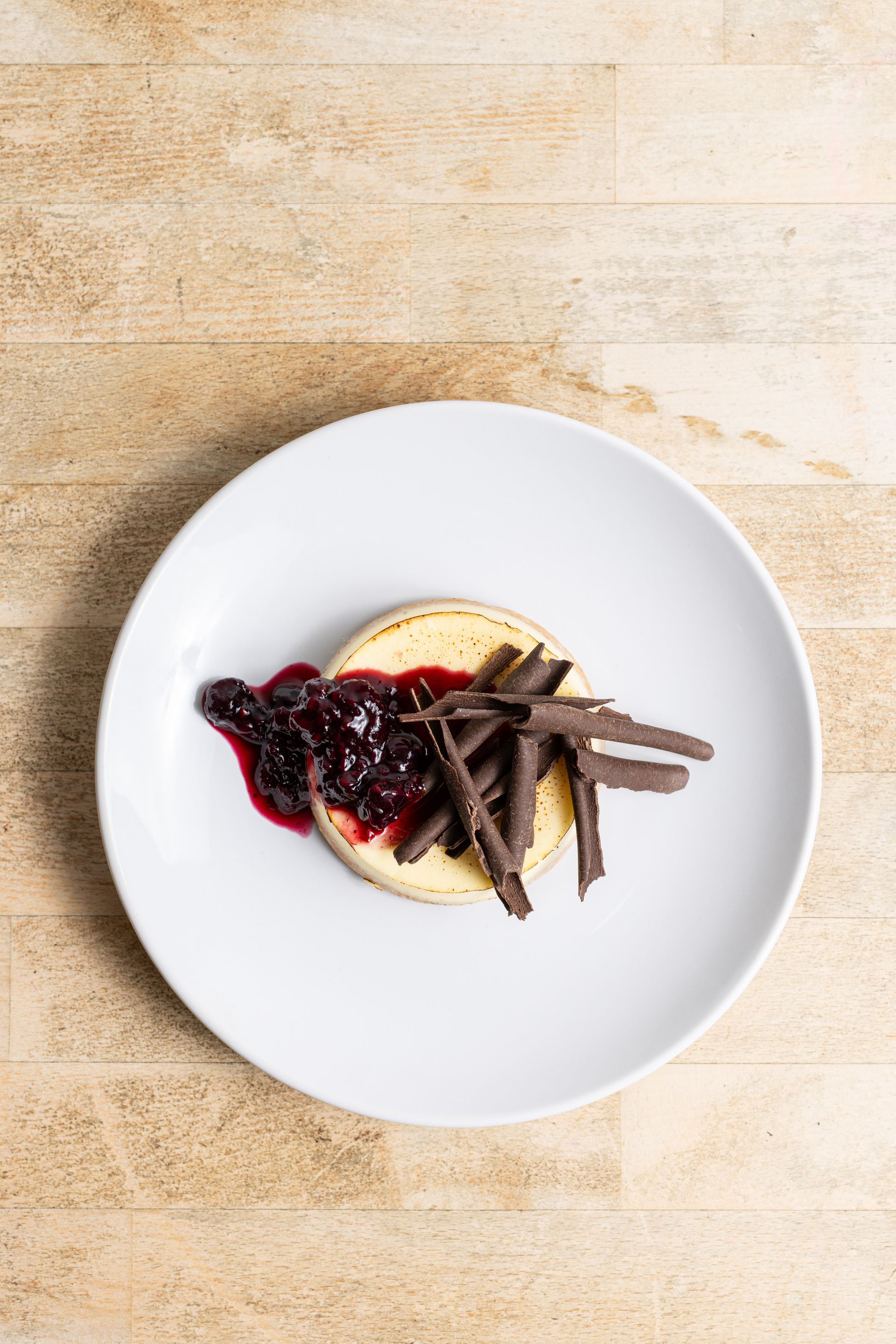 A white plate topped with a dessert and chocolate shavings on a wooden table.
