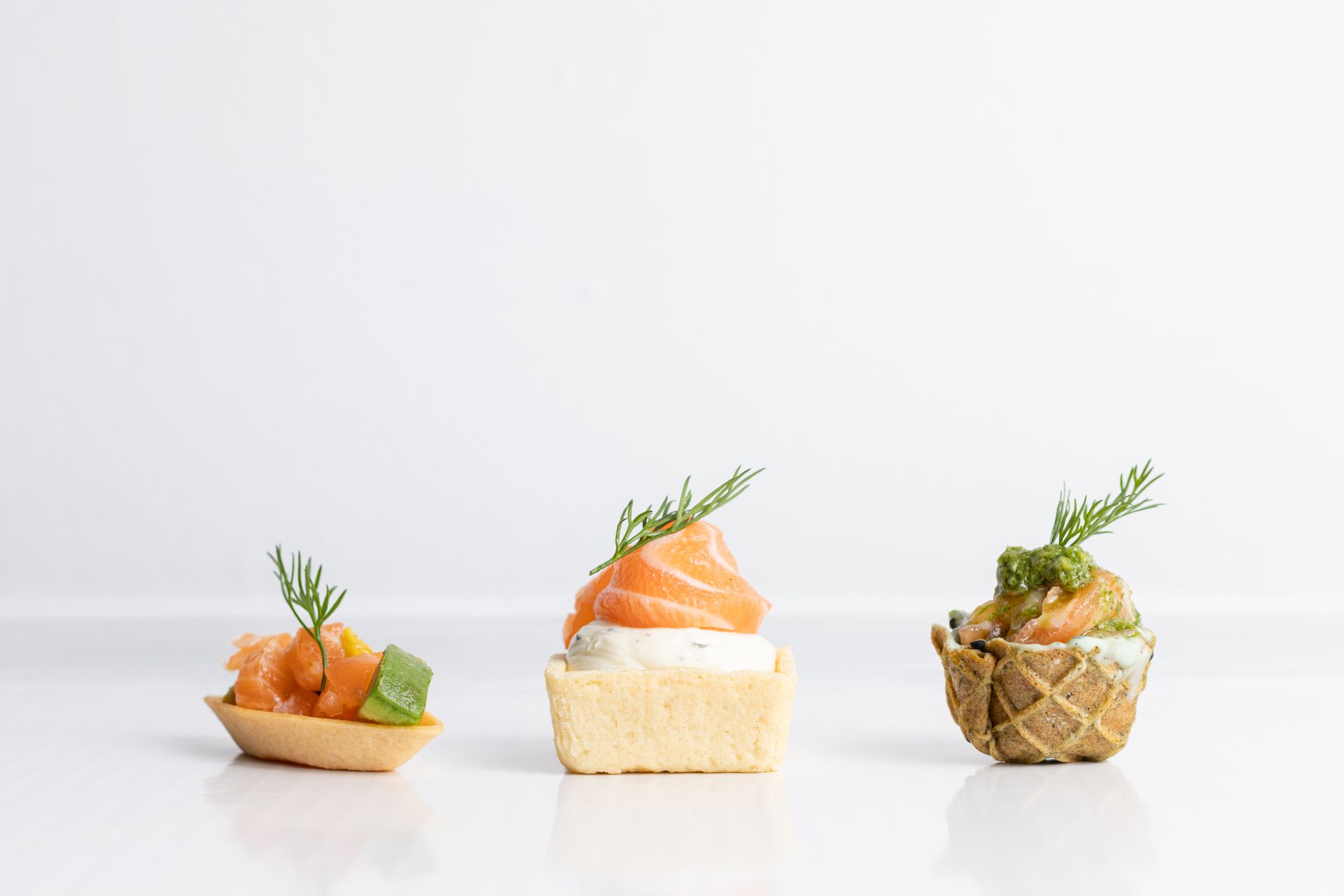 Three different types of appetizers are lined up on a white surface.